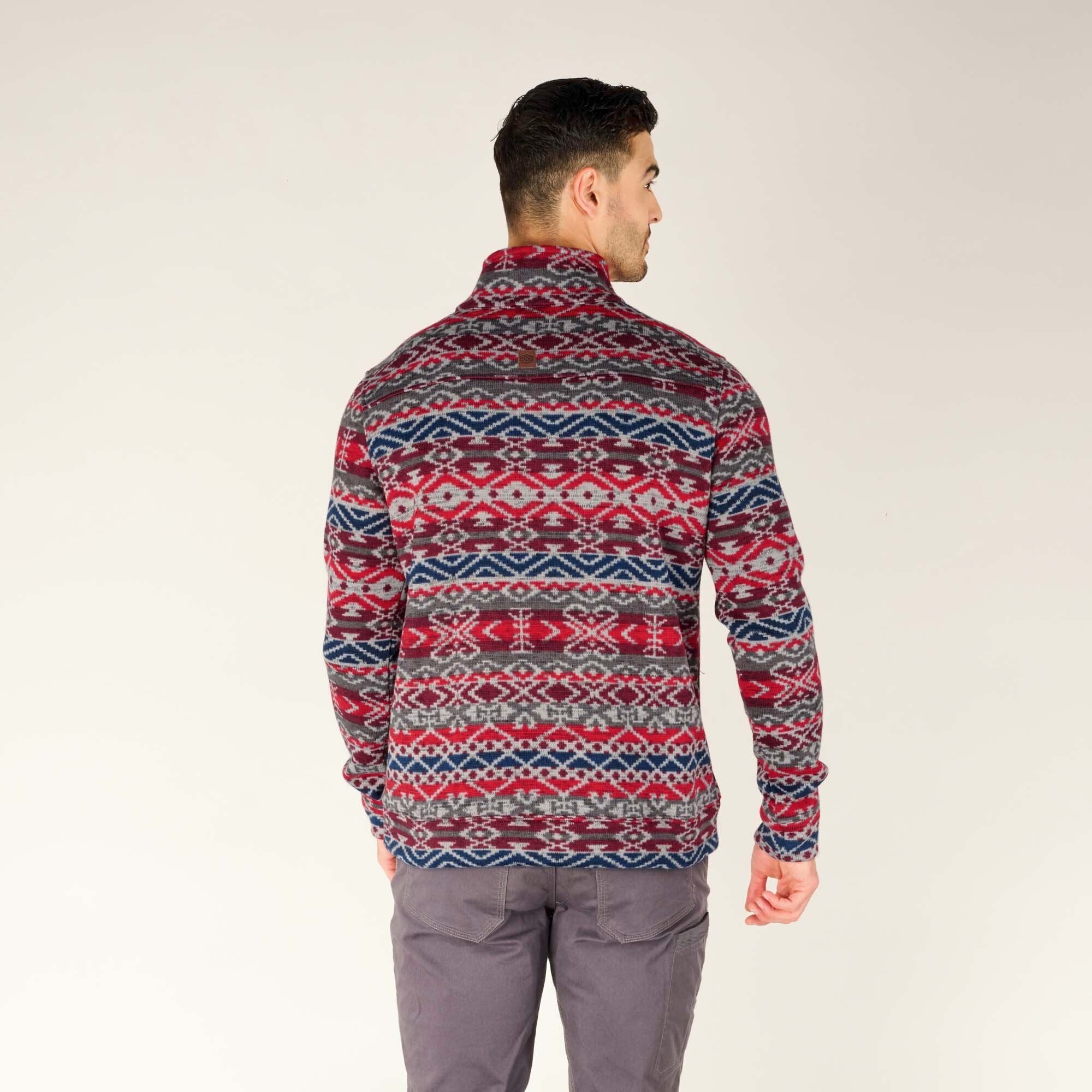 The back view of the man wearing the Sherpa Adventure Gear Bhutan Pullover in Blue, showing the uninterrupted continuation of the geometric pattern across the back. The high neck and overall fit of the pullover are visible from this angle.