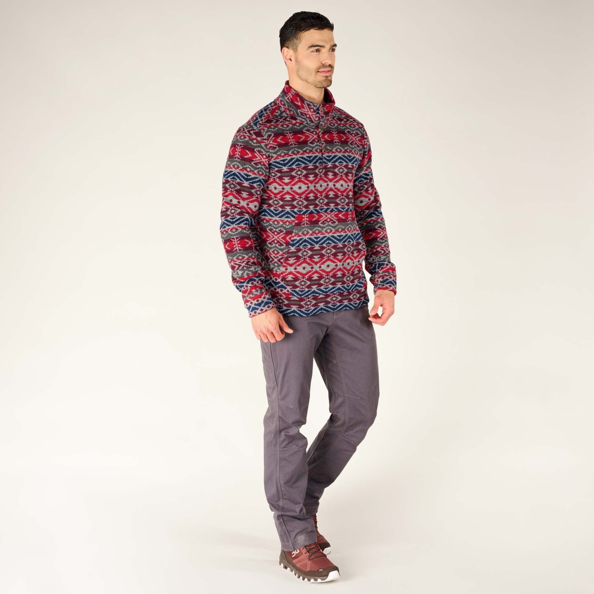 Another full-body image of the man wearing the patterned Sherpa Adventure Gear Bhutan Pullover in Blue. He stands in a relaxed pose with one foot slightly forward, showcasing the pullover's versatility as a comfortable yet stylish outdoor garment.