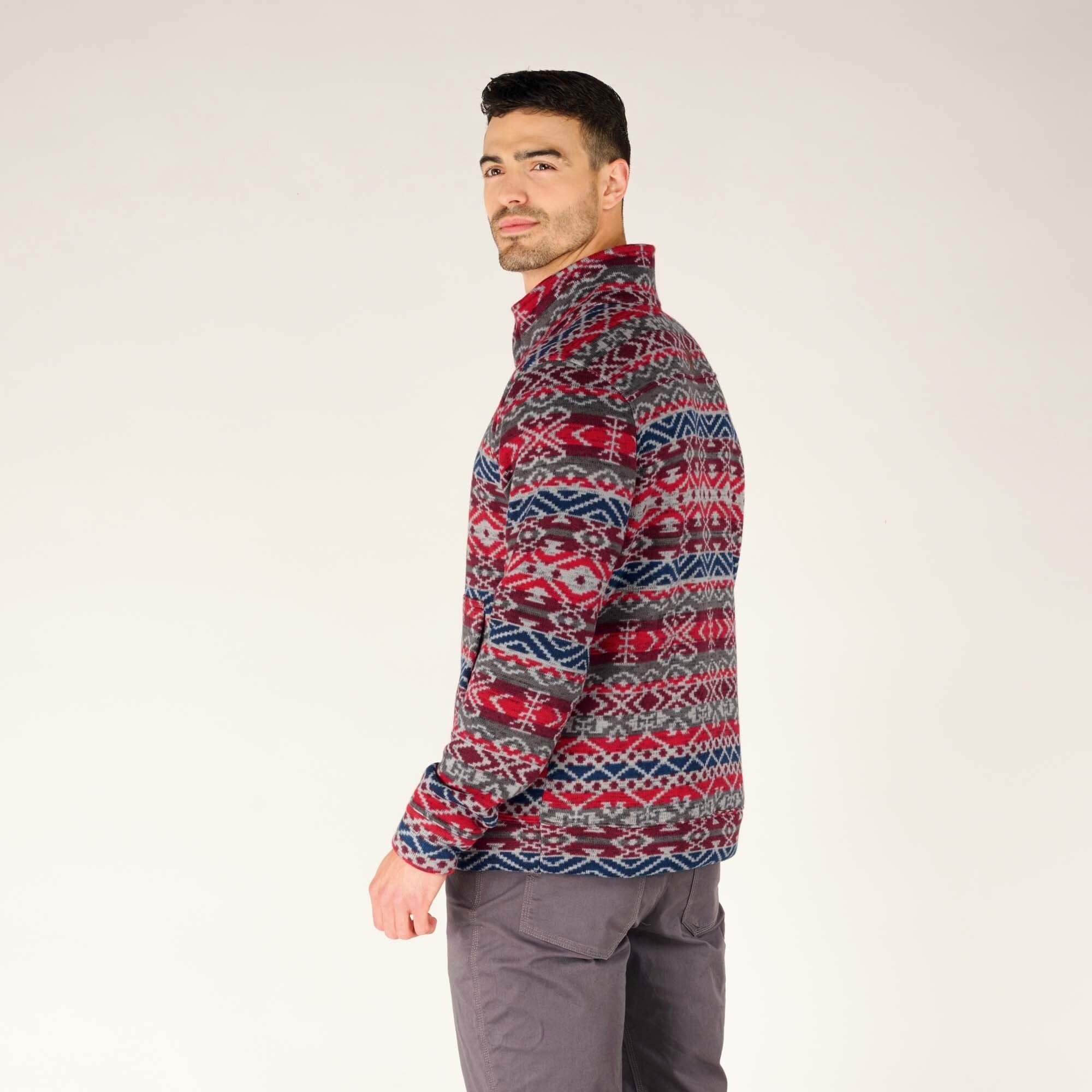 A side-profile image of the man slightly turned away from the camera, emphasising the side details and how the pattern wraps around the Sherpa Adventure Gear Bhutan Pullover in Blue. The combination of traditional design and modern fit is prominently displayed.