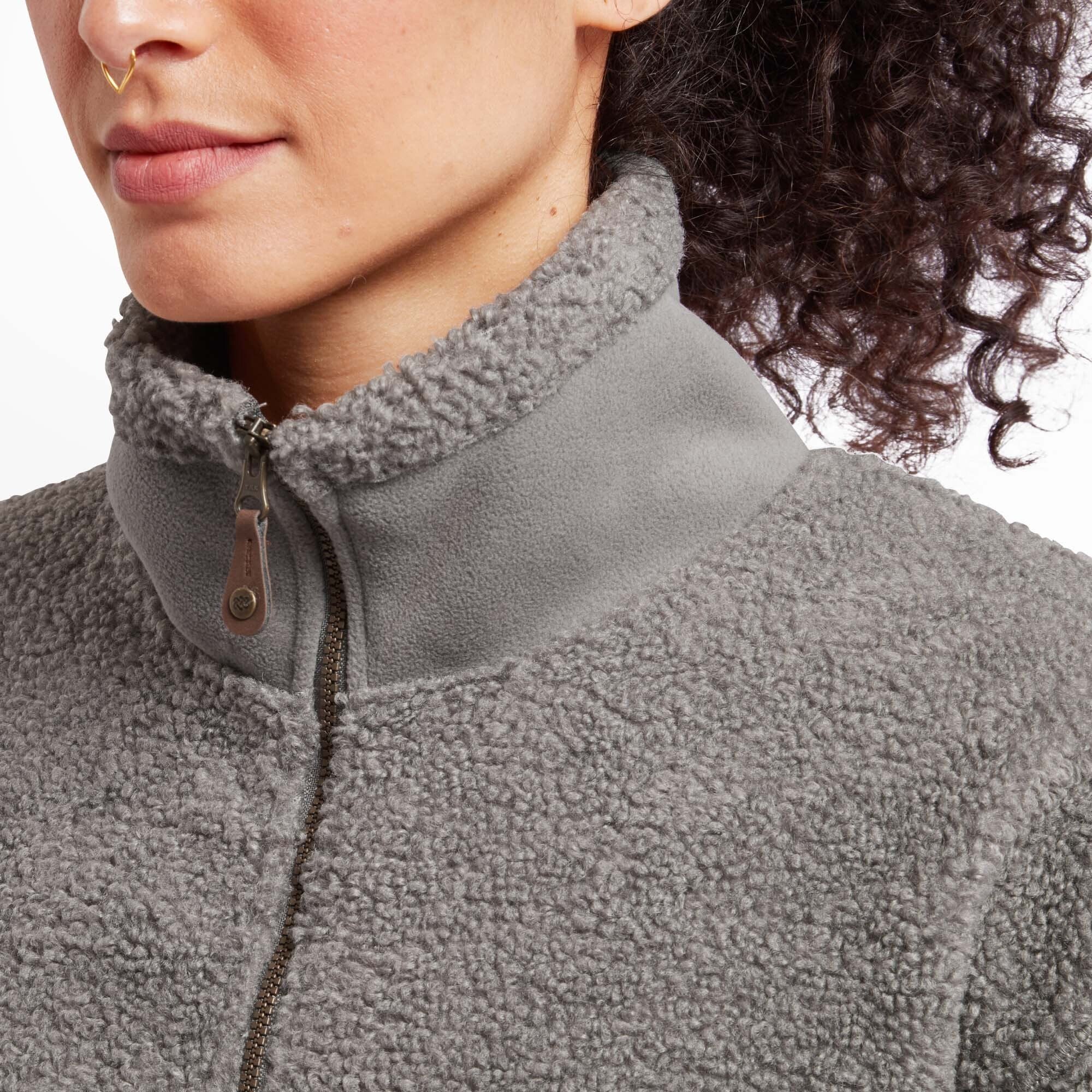 A close-up of the high collar of the Sherpa Adventure Gear Chamlang Half Zip Pullover in Grey, showing the zipper detail with a leather pull tab. The soft, textured fleece and contrasting smooth inner collar lining enhance the pullover's design details.