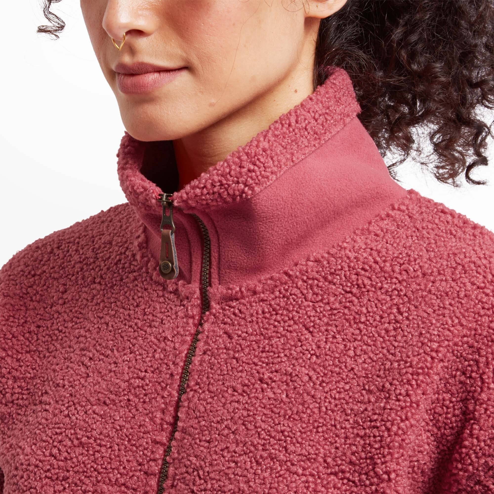 A close-up of the Sherpa Adventure Gear Chamlang Half Zip Pullover in Red's collar and half-zip closure. The red fleece is complemented by a sturdy zipper with a decorative pull tab, and the collar appears soft and snug.