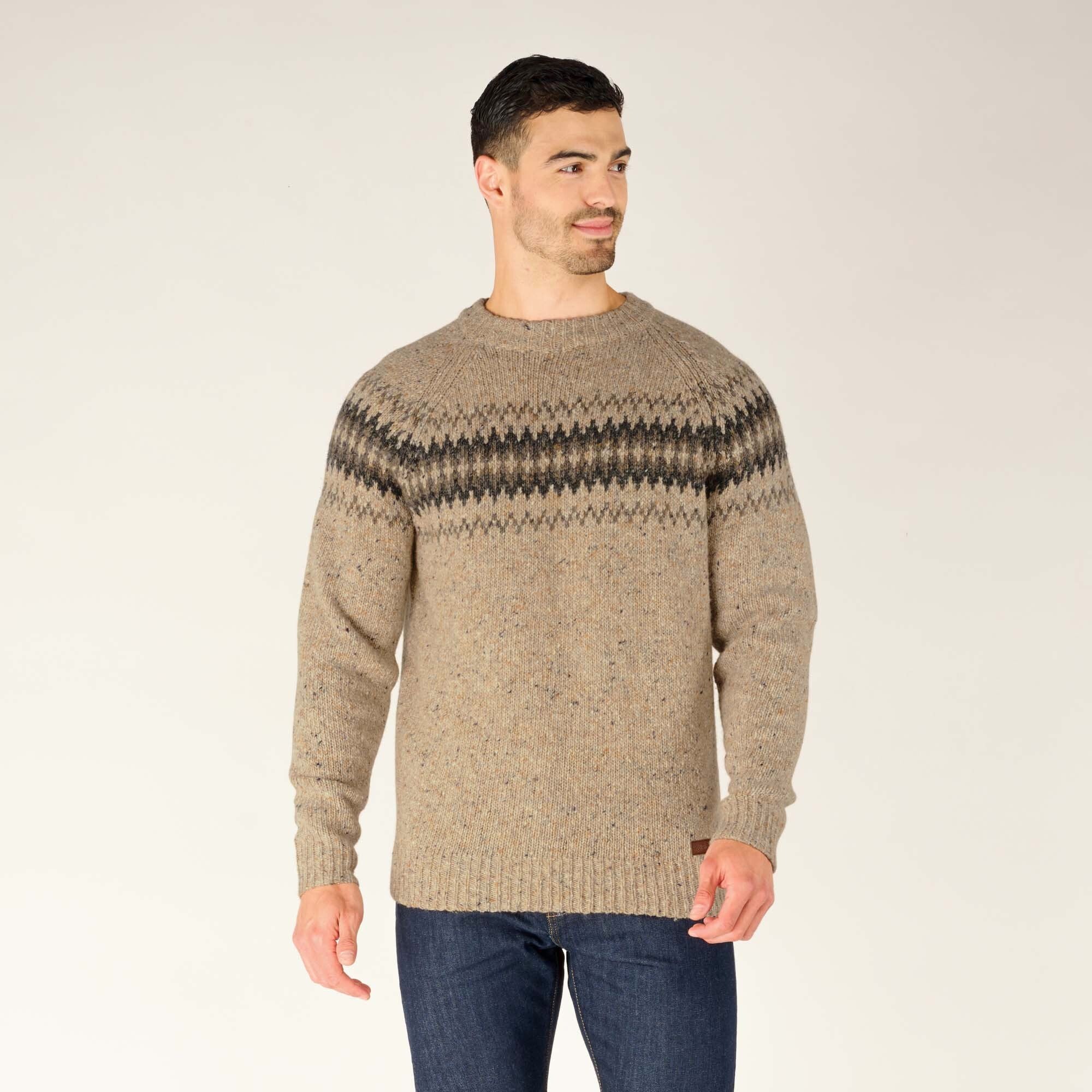 Standing straight with hands relaxed, the man confidently wears the Sherpa Adventure Gear Dumji Sweater in Beige. The ribbed crew neckline and patterned chest design draw attention, while his relaxed posture highlights the sweater's classic and functional style.