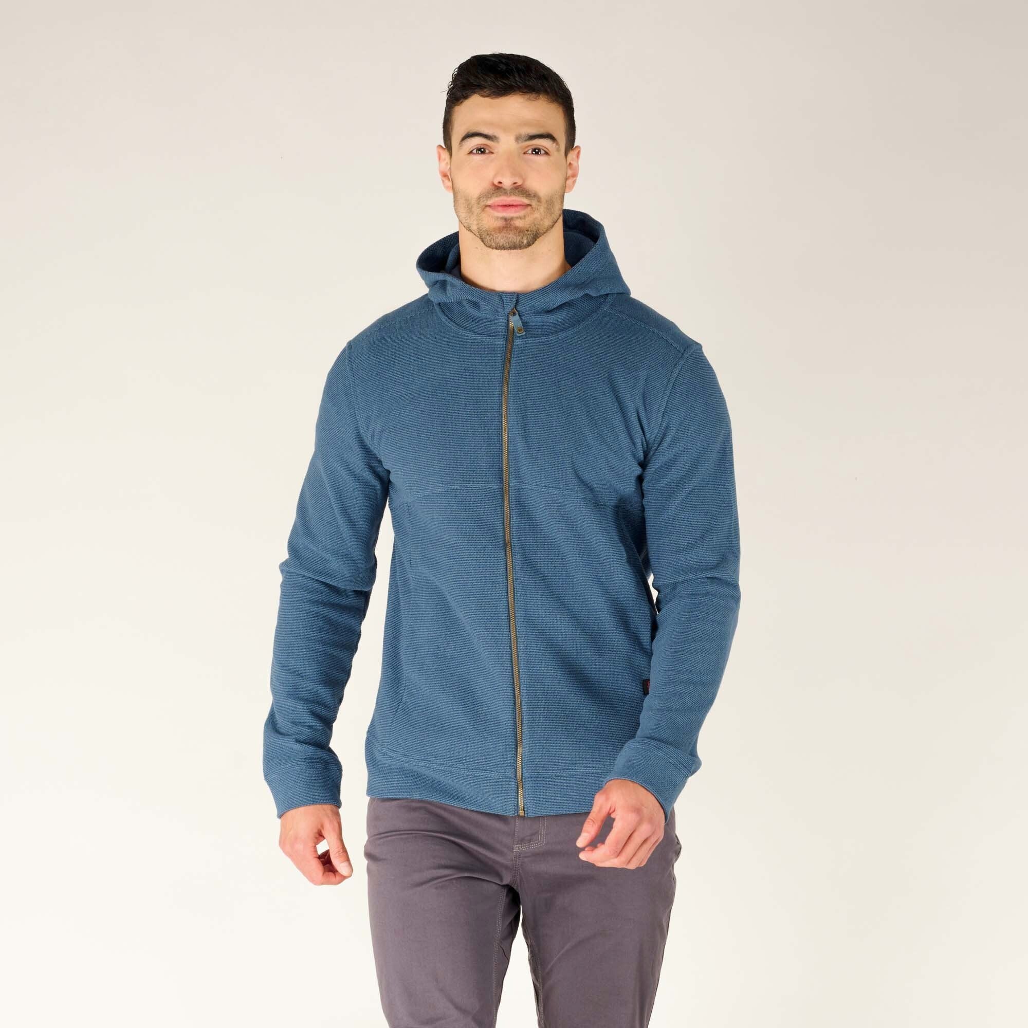 The man wearing the Sherpa Adventure Gear Kula Full Zip Hoodie in Blue fully zipped up, with the hood down. He faces forward, highlighting the hoodie’s fitted look and simple yet functional design.