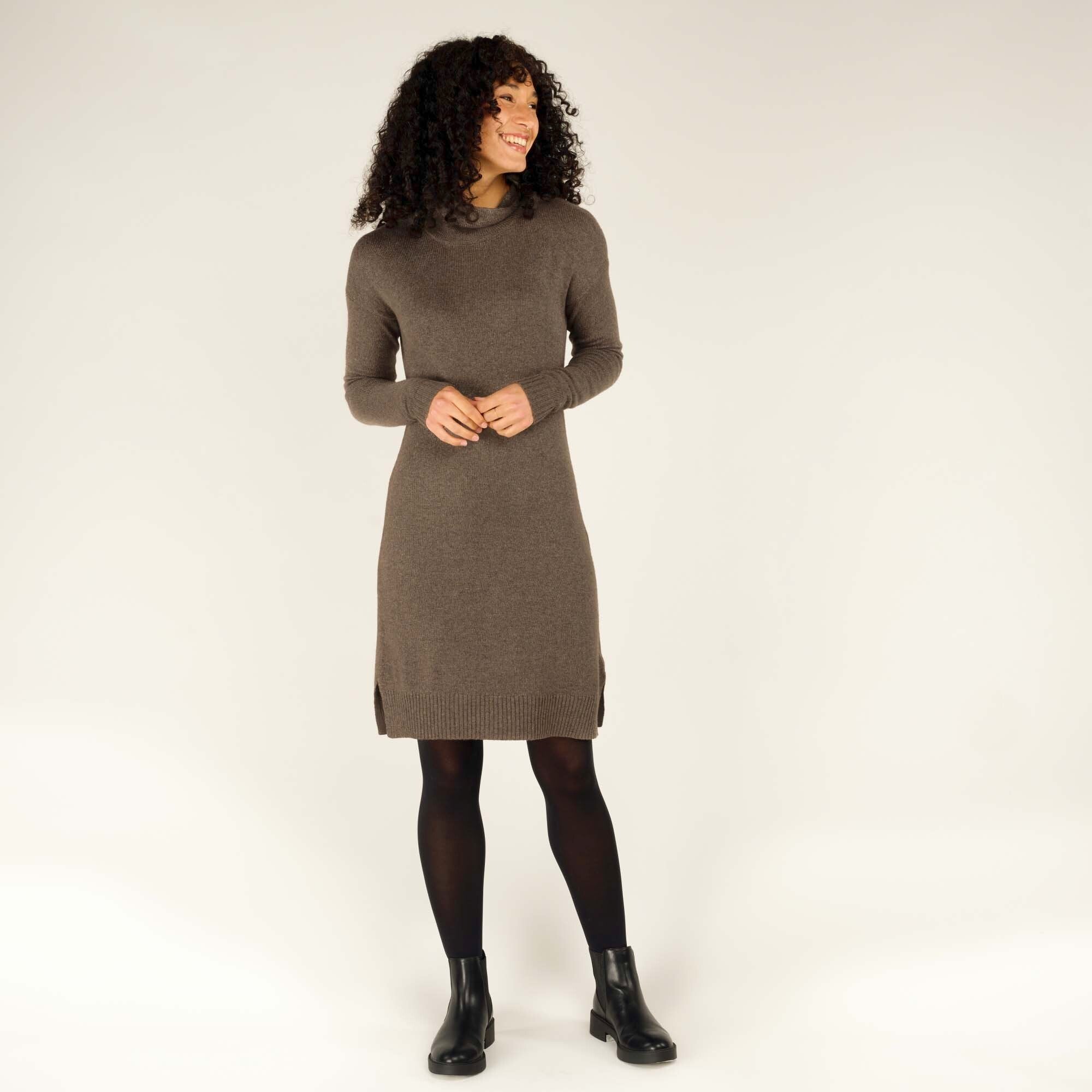 Full-body shot of the woman in the Sherpa Adventure Gear Lhakpa Mock Neck Dress in Grey paired with black tights and ankle boots. She stands relaxed, smiling warmly, showcasing how the dress pairs well with accessories for a complete look.