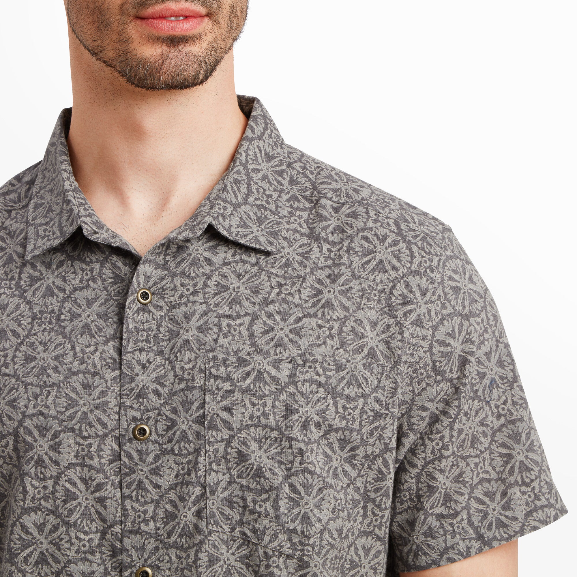 A zoomed-in view of the Sherpa Adventure Gear Mancari Short Sleeve Shirt in Grey’s upper chest area, highlighting the intricate grey geometric pattern. The fabric texture and stitching around the button placket and chest pocket are clearly visible. The buttons are small and understated.