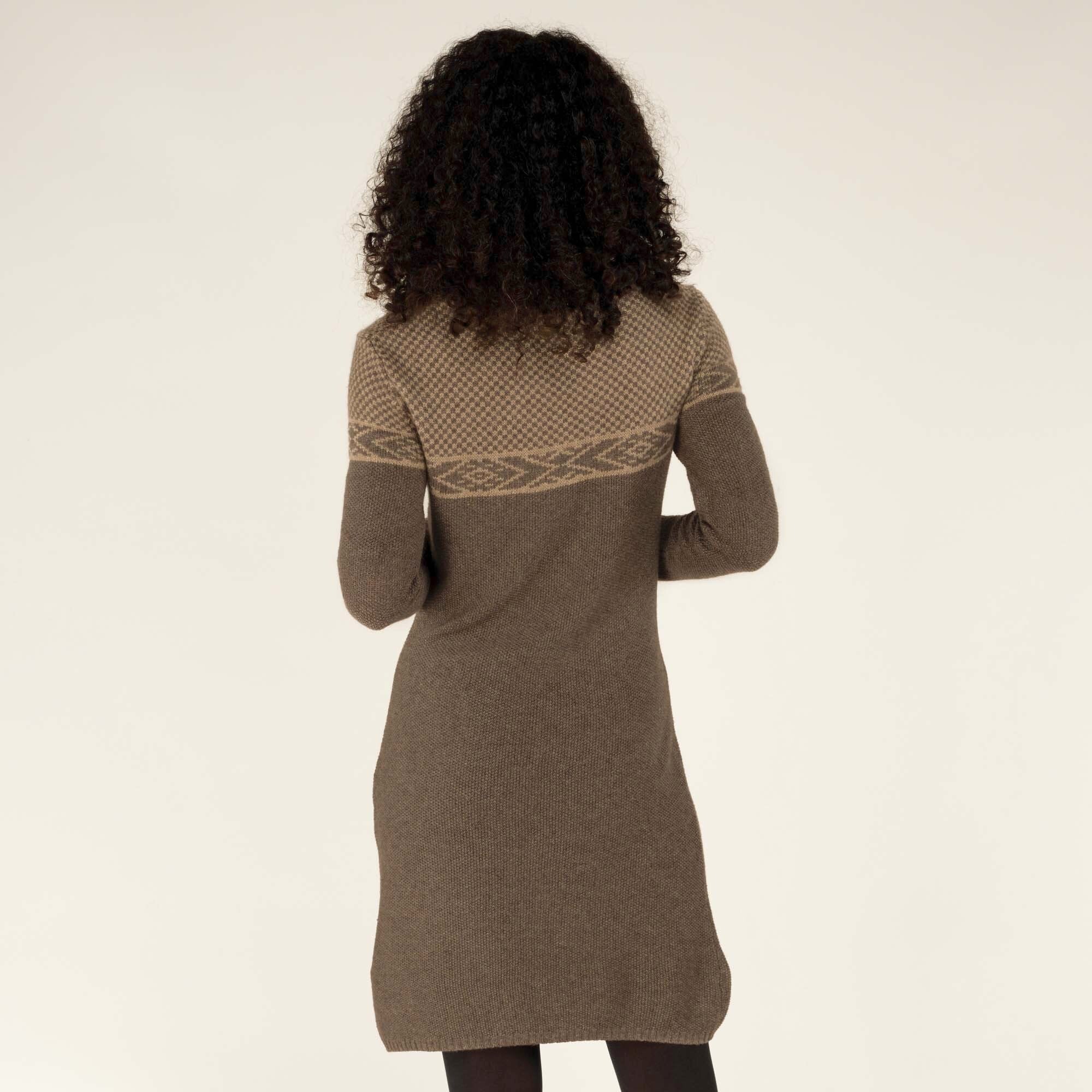 The back view of the Sherpa Adventure Gear Maya Texture Dress in Grey, highlighting its clean and seamless construction. The geometric design extends across the upper back, complementing the overall elegant design. The model stands with her arms slightly bent at her sides.