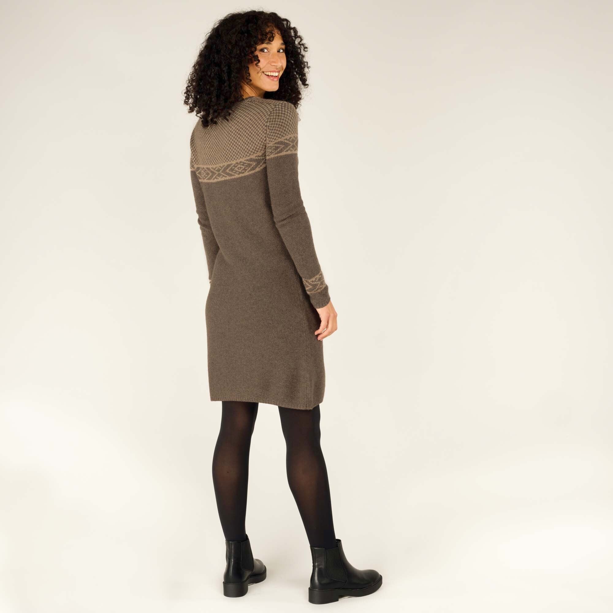 A playful pose with the model turning slightly to look behind her, smiling brightly. The image highlights the full outfit, including black tights and black ankle boots, giving a complete styled look for this versatile Sherpa Adventure Gear Maya Texture Dress in Grey.