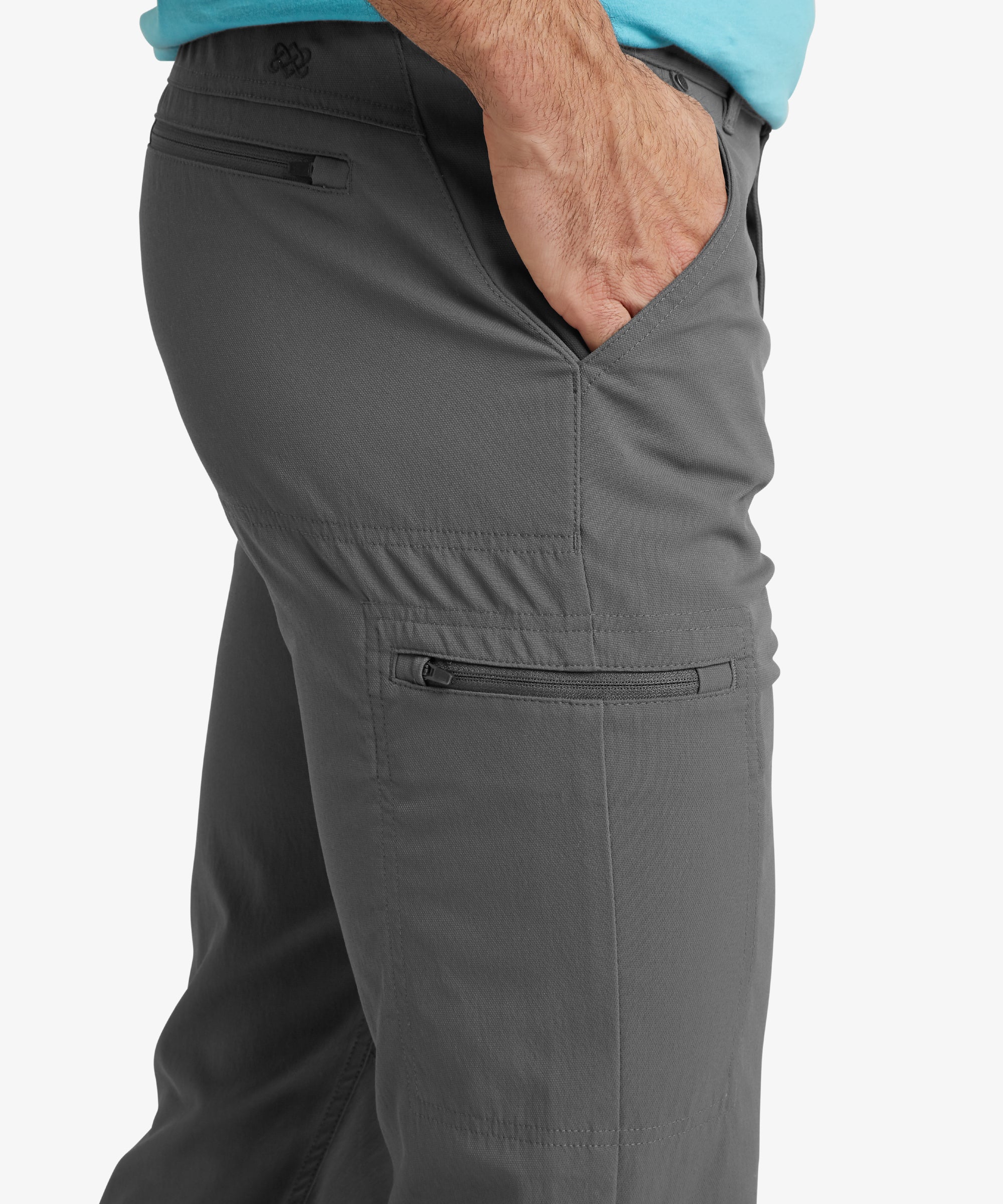 A close-up of the Sherpa Adventure Gear Bara trousers in Grey's side pocket as a hand slides in, emphasising the functional and accessible design of the trousers. The sleek stitching and durable fabric are clearly displayed.