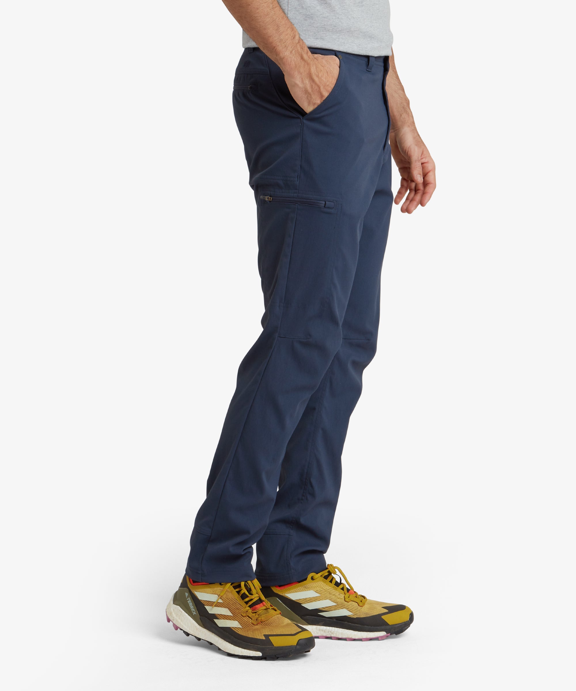 Rear view of the model showing the back of the Sherpa Adventure Gear Bara trousers in Blue. Features include well-positioned back pockets with zip closures for secure storage. The tapered leg design provides a flattering fit, while the overall style is versatile and modern, perfect for outdoor or casual settings.