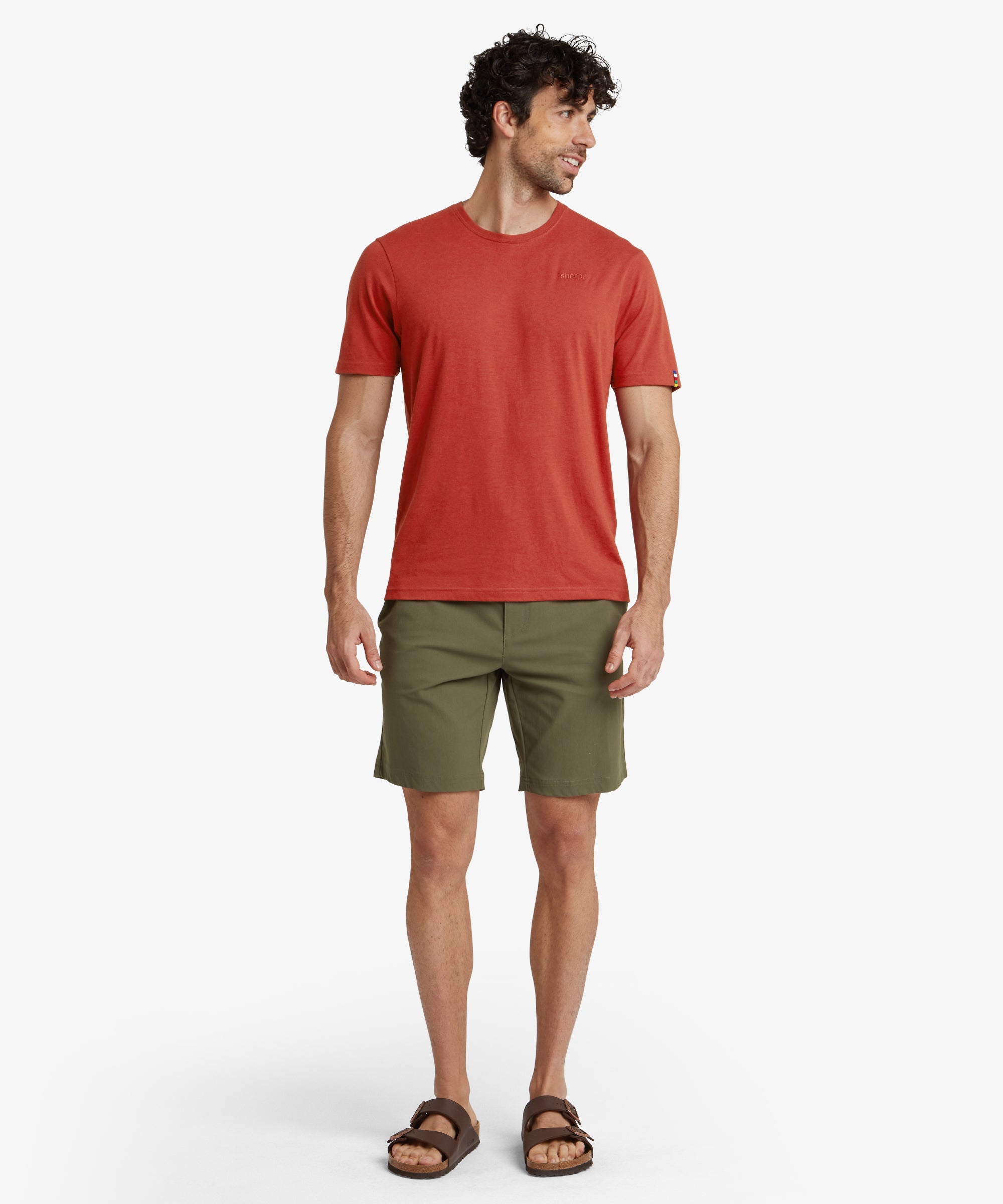 A side profile of the Sherpa Adventure Gear Bara Shorts in Green, showing the angled side pockets and smooth stitching for a polished finish. The shorts have a neat silhouette, with the model’s hand partially in the pocket, highlighting its functionality.