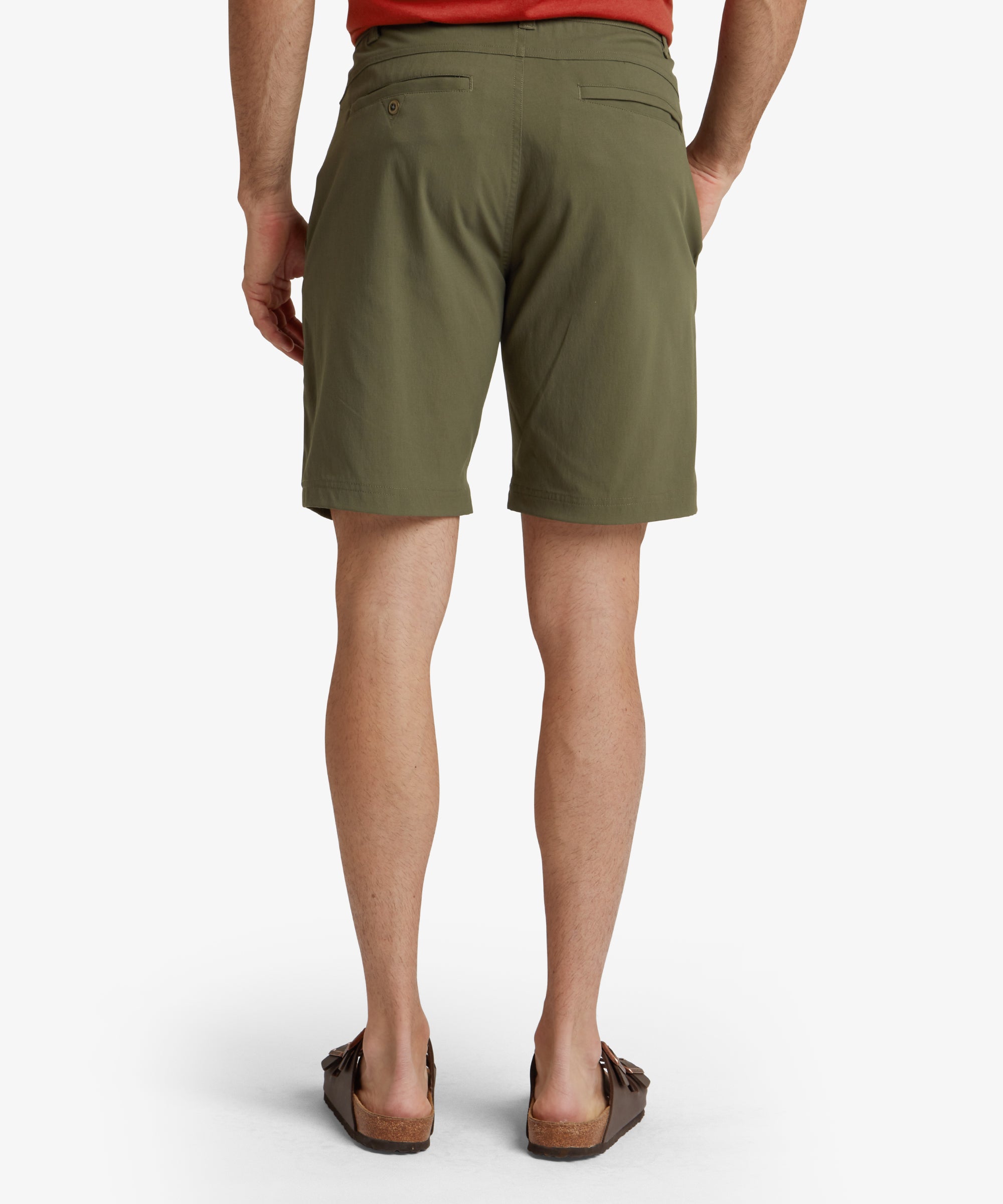 A slightly angled back-side view showcasing both the back pocket details and the overall fit of the Sherpa Adventure Gear Bara Shorts in Green. The model's stance highlights the streamlined and ergonomic design.