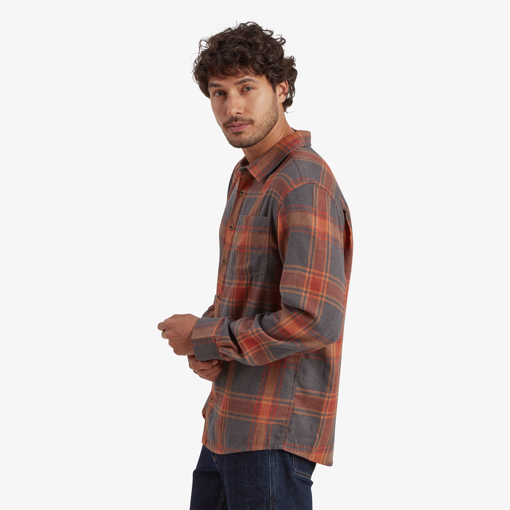 A profile view of the model wearing the Sherpa Adventure Gear Batsa Long Sleeve Shirt in Red. This angle shows the shirt's straight hemline and slightly loose fit around the shoulders, emphasising its comfortable and practical design.