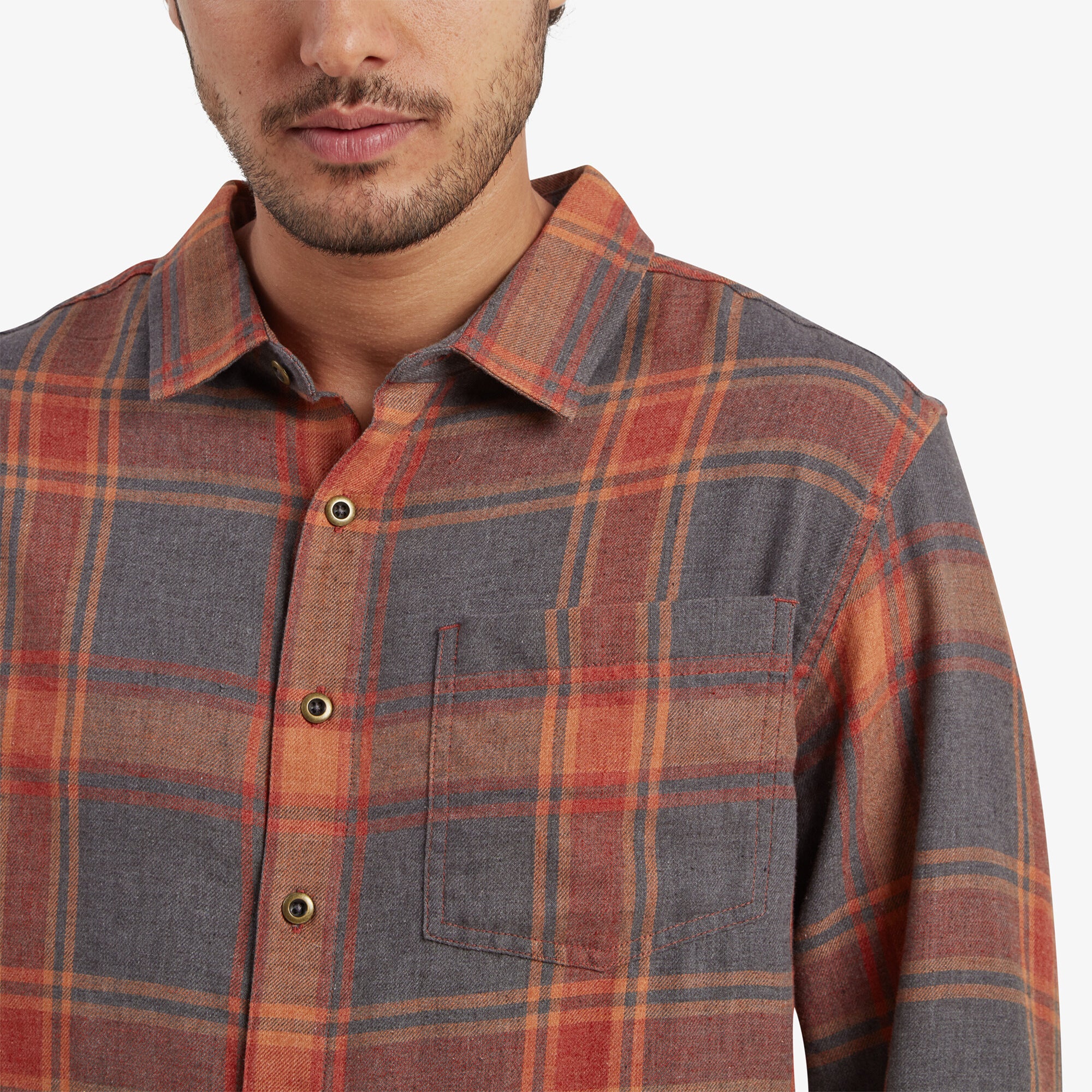 A detailed close-up of the Sherpa Adventure Gear Batsa Long Sleeve Shirt in Red's chest pocket and buttoned collar. The plaid pattern and texture of the fabric are clearly visible, highlighting the craftsmanship and material quality.