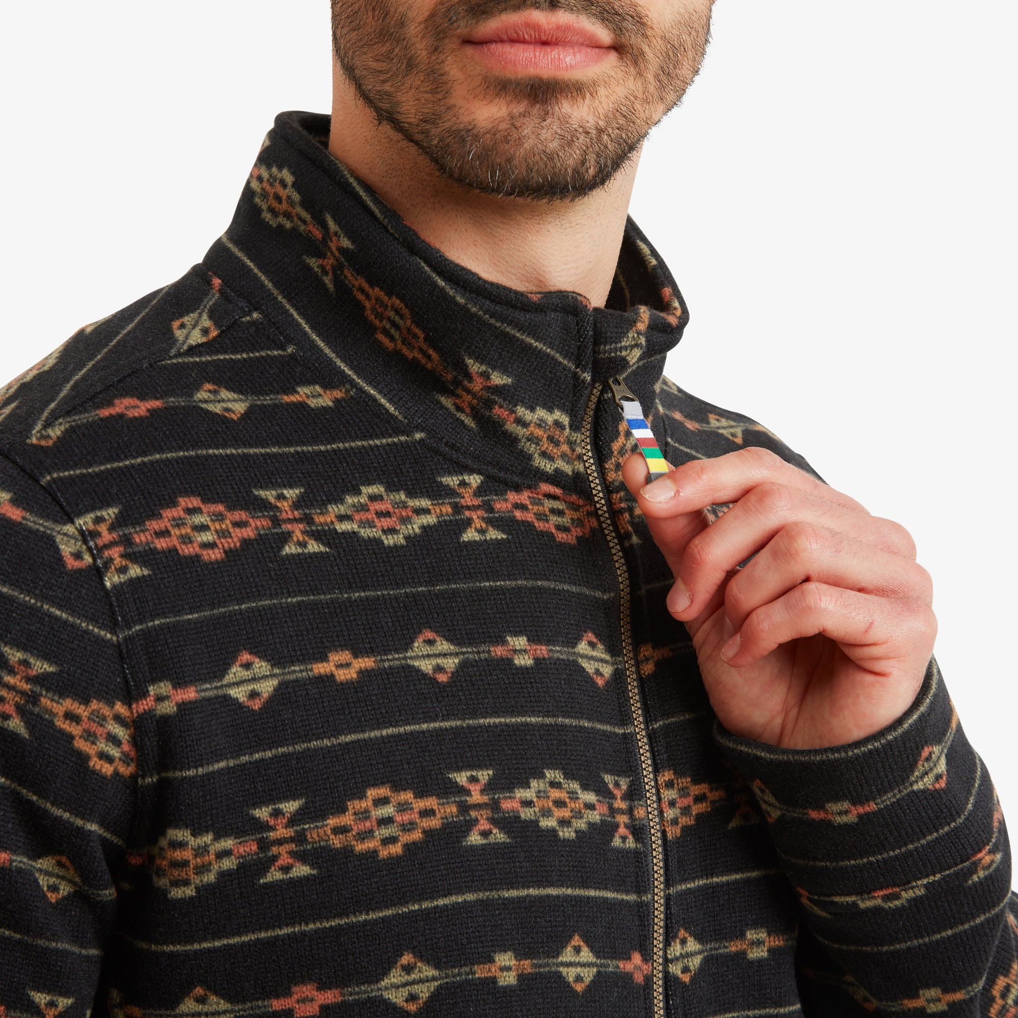 A detailed shot focusing on the high collar and zipper on the Sherpa Adventure Gear Bhutan Full Zip Jacket in Black, showcasing the vibrant colors of the zipper pull with Sherpa's signature multicolored stripes. The fabric texture is clearly visible, emphasising its premium quality and craftsmanship.