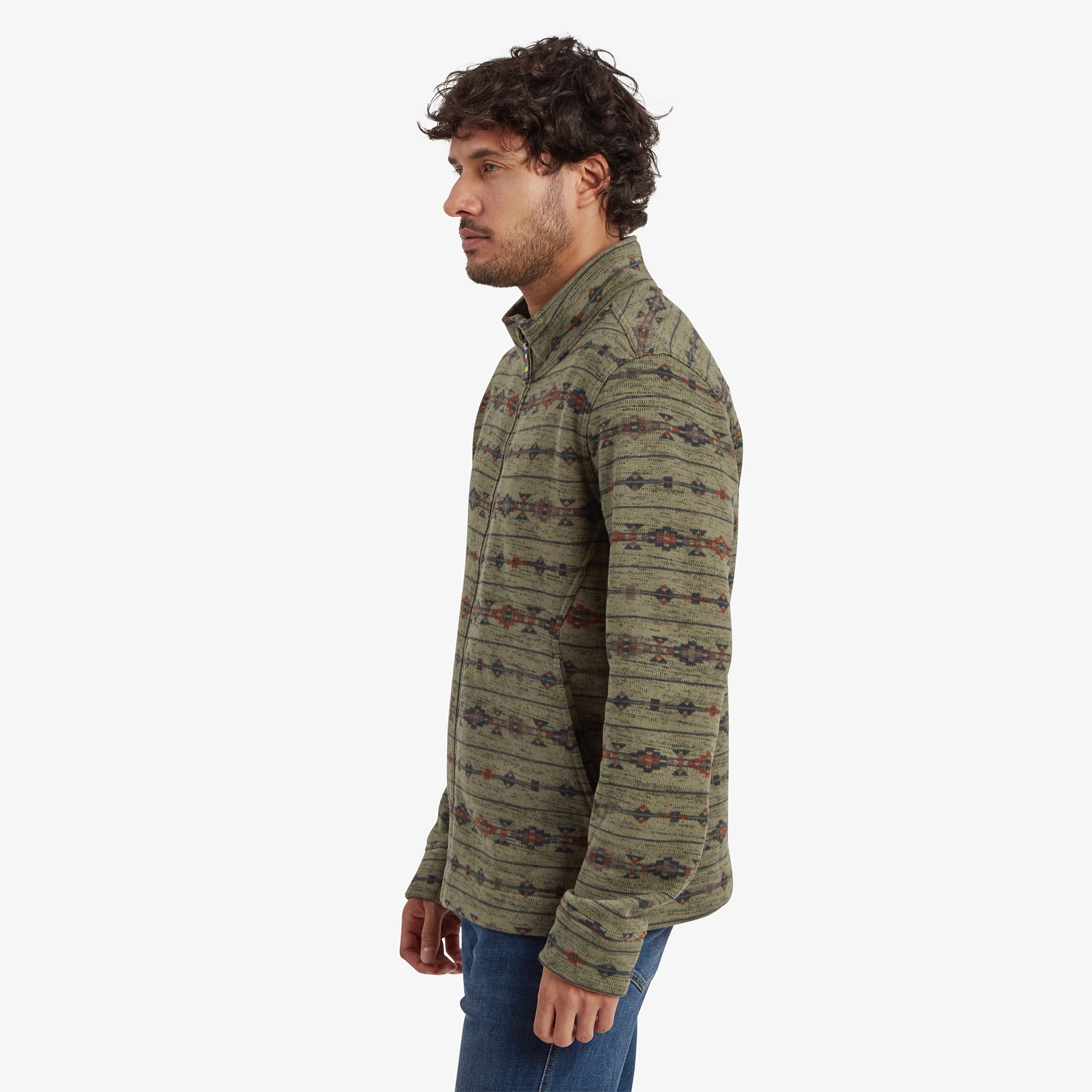 The model is turned slightly to the left, showcasing the Sherpa Adventure Gear Bhutan Full Zip Jacket in Green's side seam and the subtle pattern continuity on the sleeves and body. The side pockets are partially visible, and the model maintains a relaxed posture.