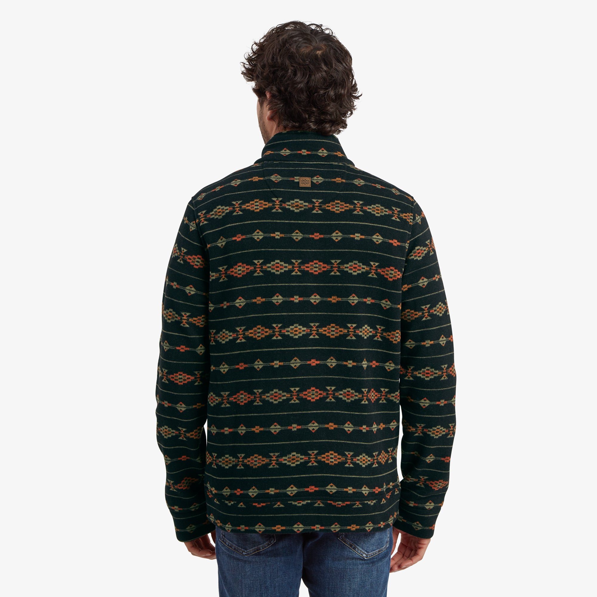 The back view of the Sherpa Adventure Gear Bhutan Pullover in Black. The intricate geometric pattern continues seamlessly, and the man is standing with a relaxed posture. A small logo patch is visible near the upper back of the pullover.