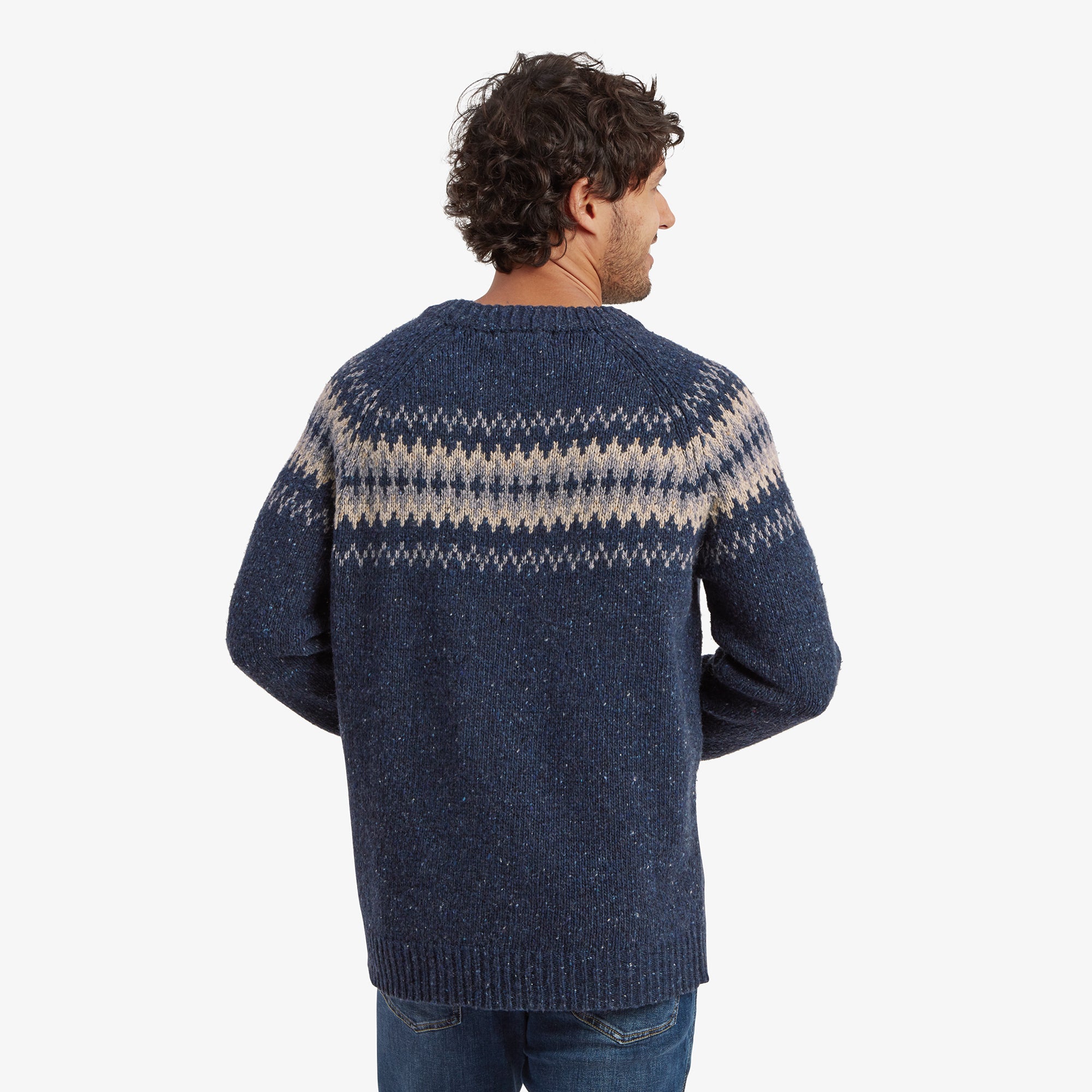 The Sherpa Adventure Gear Dumji Sweater in Blue's back is showcased, revealing the seamless extension of the geometric pattern across the shoulders and upper back. The bottom hem and sleeves have ribbed cuffs for added structure.