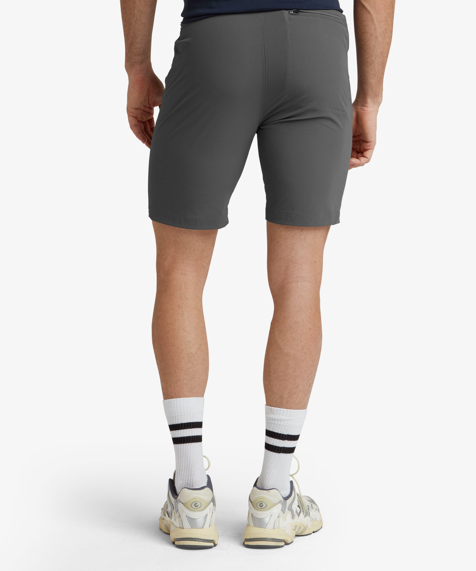 A full back and side perspective of the Sherpa Adventure Gear Jamyang Shorts in Grey, with the model standing naturally. The image highlights the shorts' length, hitting just above the knee, and the streamlined fit around the legs. The trainers complete the look, making the outfit ideal for outdoor or casual activities.