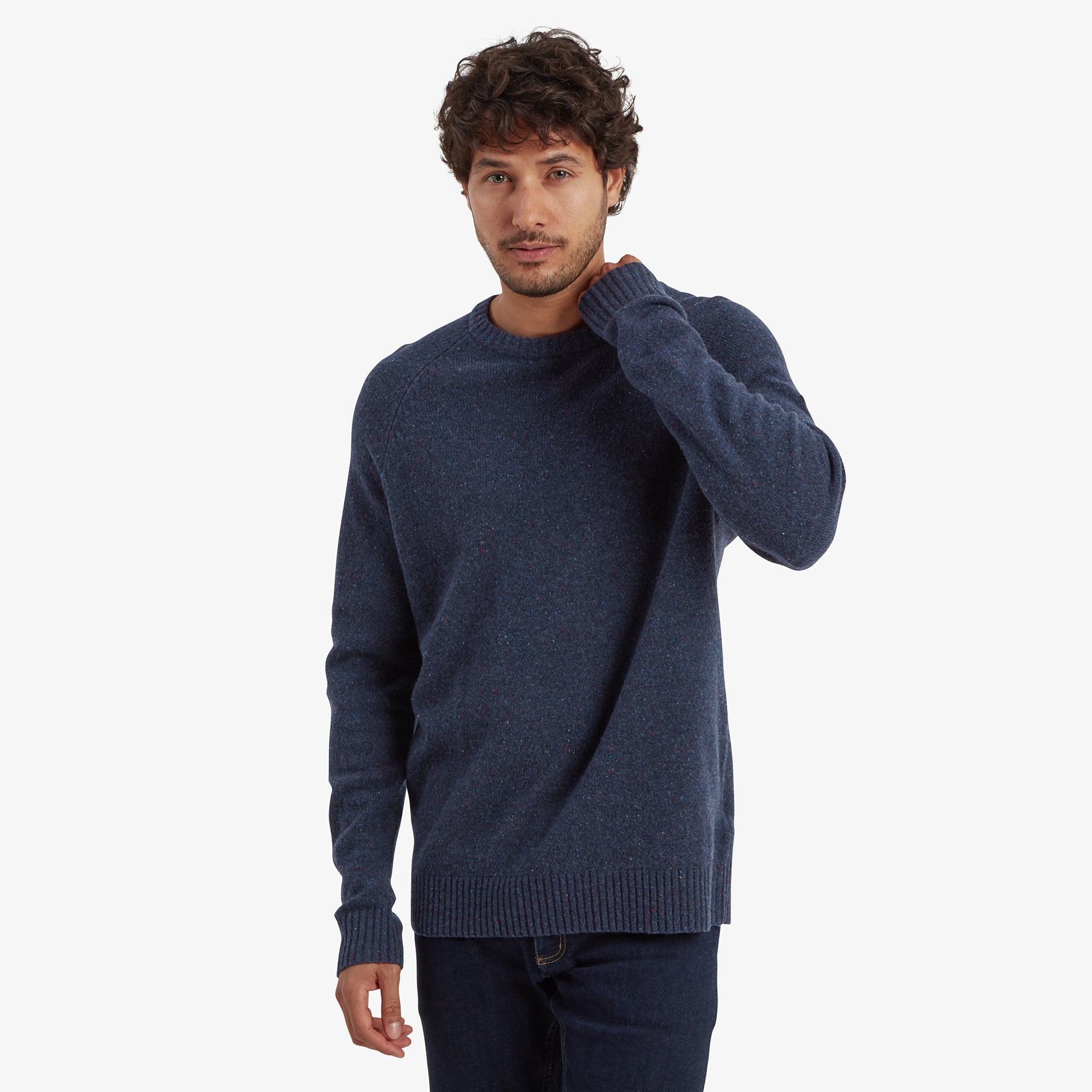 A man wearing a Sherpa Adventure Gear Kangtega Crew Sweater in Blue made of textured fabric, paired with dark blue jeans. The sweater has long sleeves and ribbed cuffs, providing a casual yet polished look.