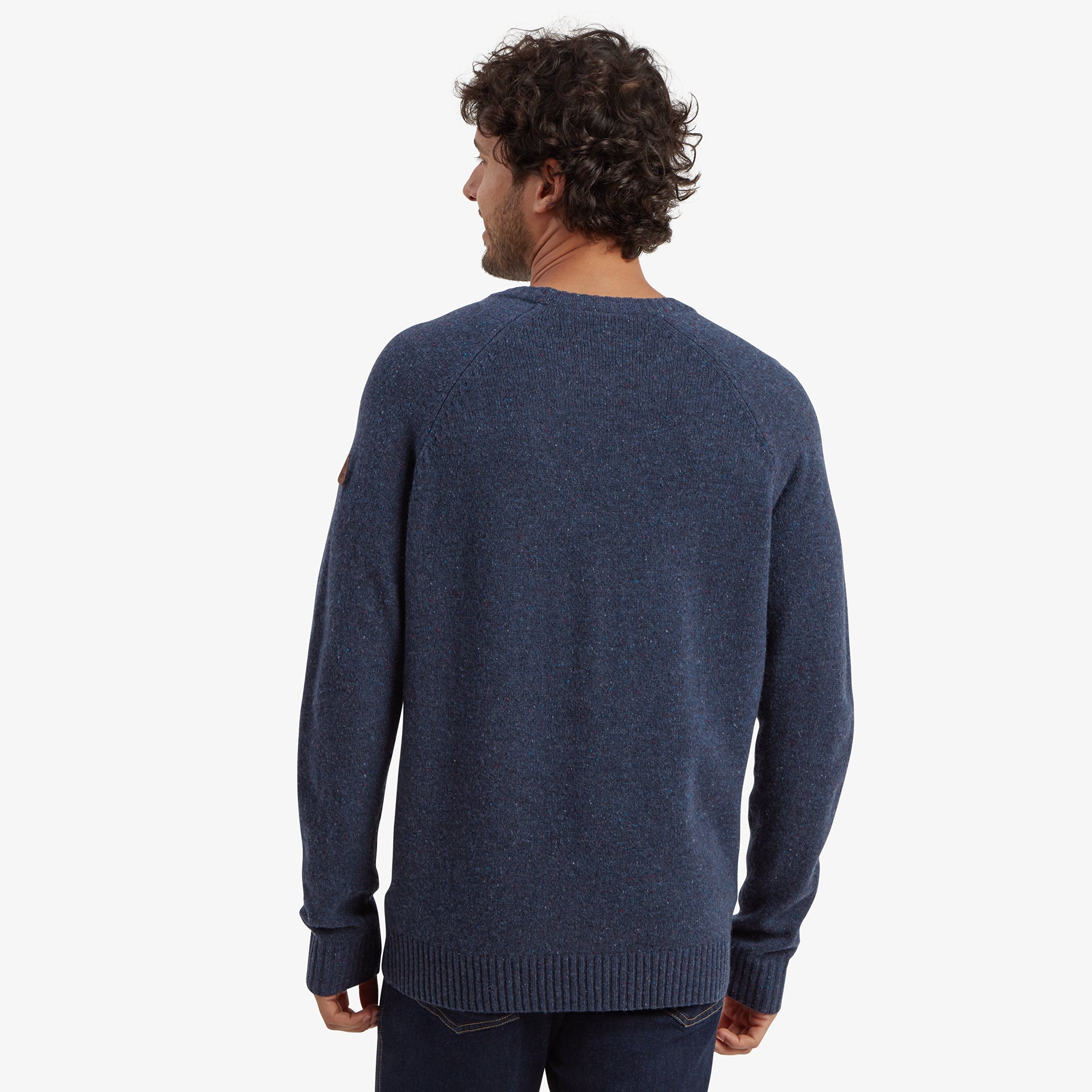 Back view of the Sherpa Adventure Gear Kangtega Crew Sweater in Blue highlighting its clean lines, classic fit, and seamless construction. The model’s hair and relaxed pose contribute to the casual style.