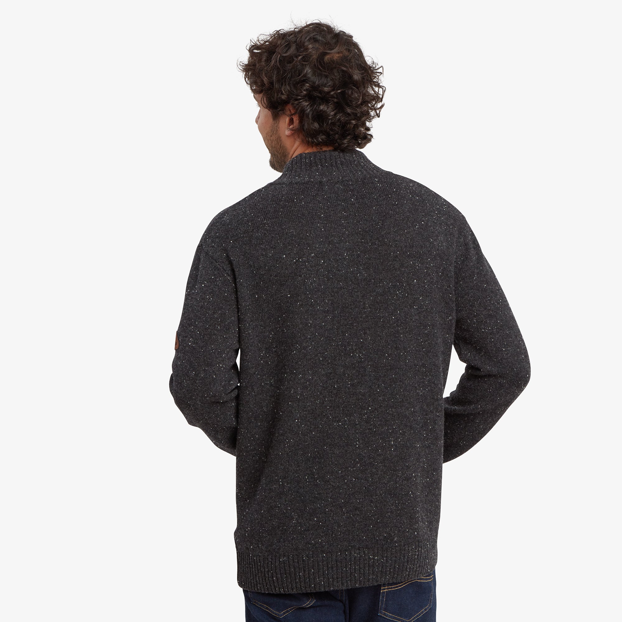 A back view of the man in the Sherpa Adventure Gear Kangtega Quarter Zip Sweater in Black, showing the simple and clean design at the back. The speckled knit texture and ribbed hem are visible, providing a clear view of the sweater's overall fit.