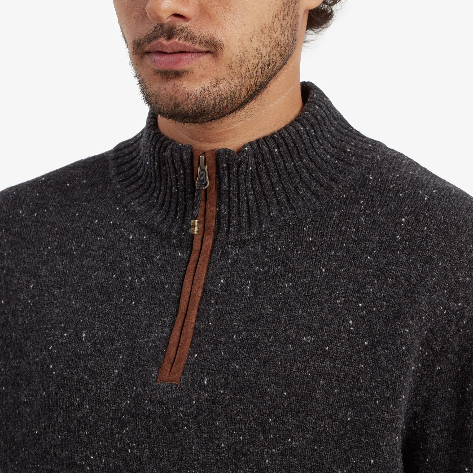 A close-up of the quarter-zip detail on the Sherpa Adventure Gear Kangtega Quarter Zip Sweater in Black, showcasing the ribbed knit collar and the suede-like zipper pull with metallic hardware. The fine speckled texture of the sweater is visible, along with the clean stitching.