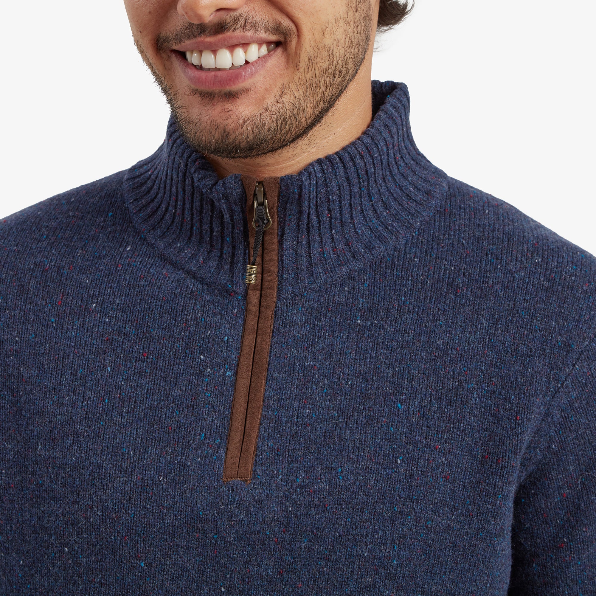 A close-up of the Sherpa Adventure Gear Kangtega Quarter Zip Sweater in Blue's sleeve displays the Sherpa logo patch, sewn in brown leather-like material, against the soft, speckled knit fabric, adding a distinctive touch.