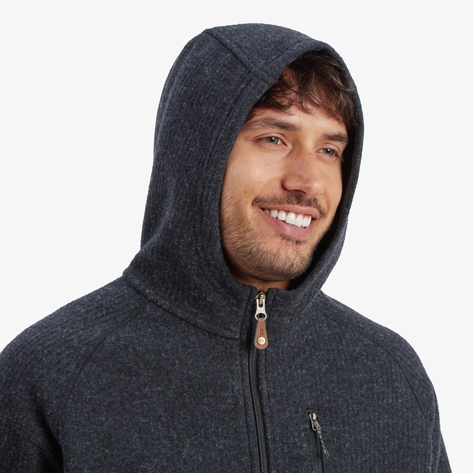 A close-up of the hood worn over the man's head. The image highlights the snug fit around the face, with a detailed look at the front zipper and its pull tab. The hood retains the Sherpa Adventure Gear Namgyal Hoodie in Black's textured charcoal fabric.