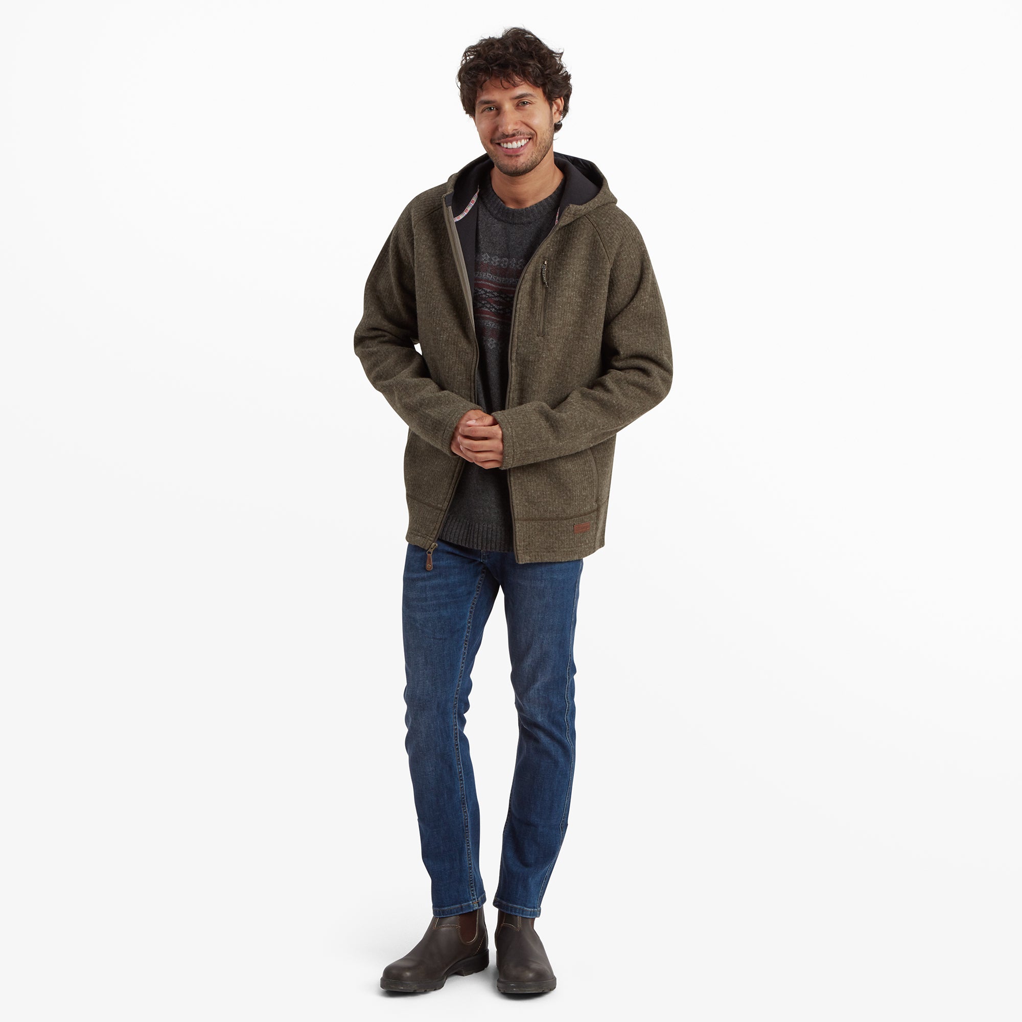 A full-body view of the model wearing the Sherpa Adventure Gear Namgyal Hoodie in Green paired with blue jeans and brown shoes. The outfit is styled casually, highlighting the versatility and warmth of the hoodie.