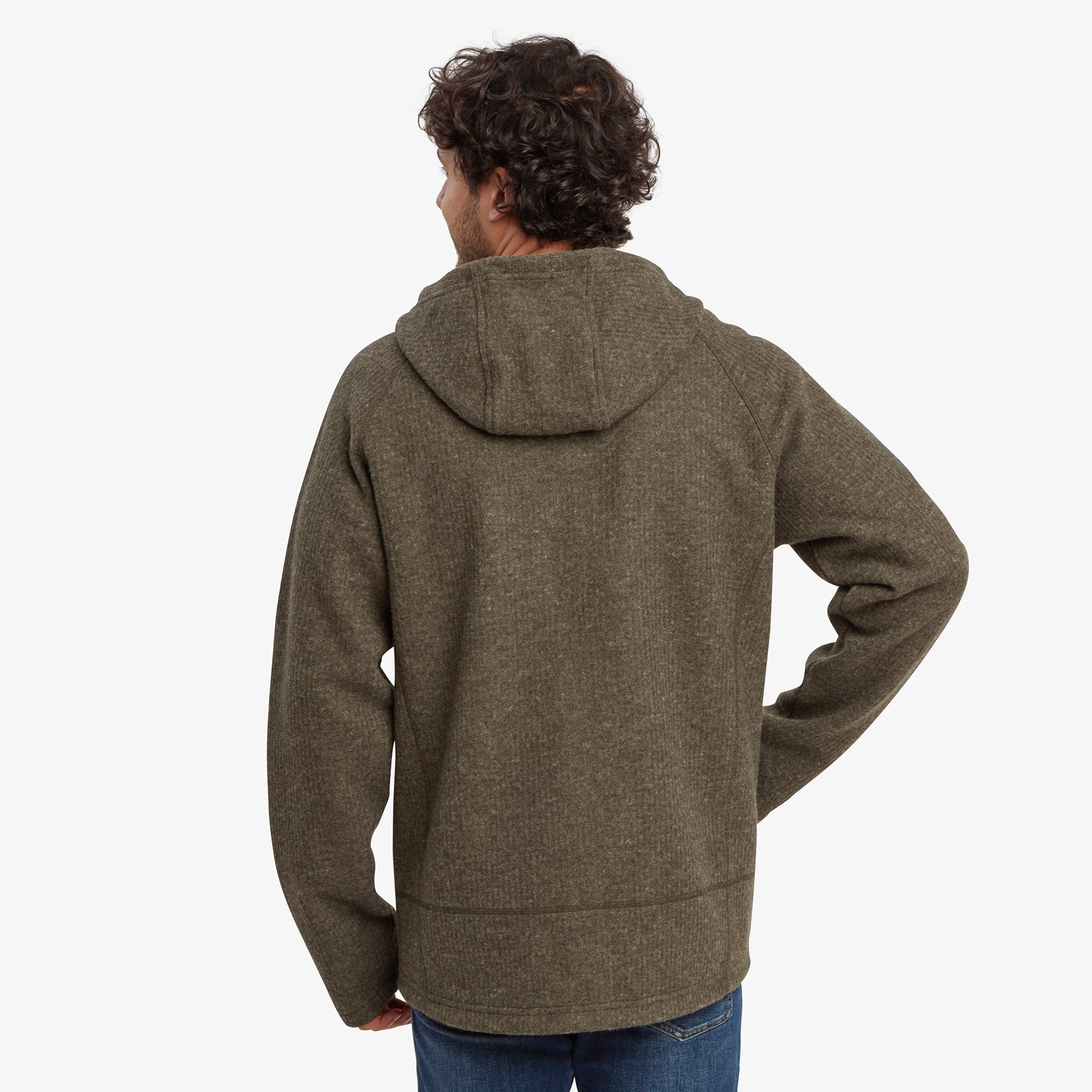 A back view of the Sherpa Adventure Gear Namgyal Hoodie in Green, showcasing the hood and the smooth, seamless design. The ribbed detailing at the hem adds structure to the hoodie.