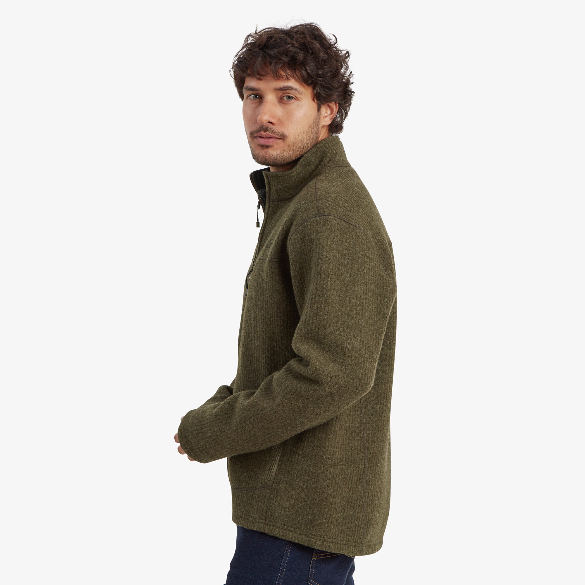 A side profile of the man wearing the Sherpa Adventure Gear Namgyal Jacket in Brown, illustrating the jacket’s fit and structure on the side. The high neck and long sleeves provide coverage and warmth, while the clean lines of the design offer a sleek silhouette.