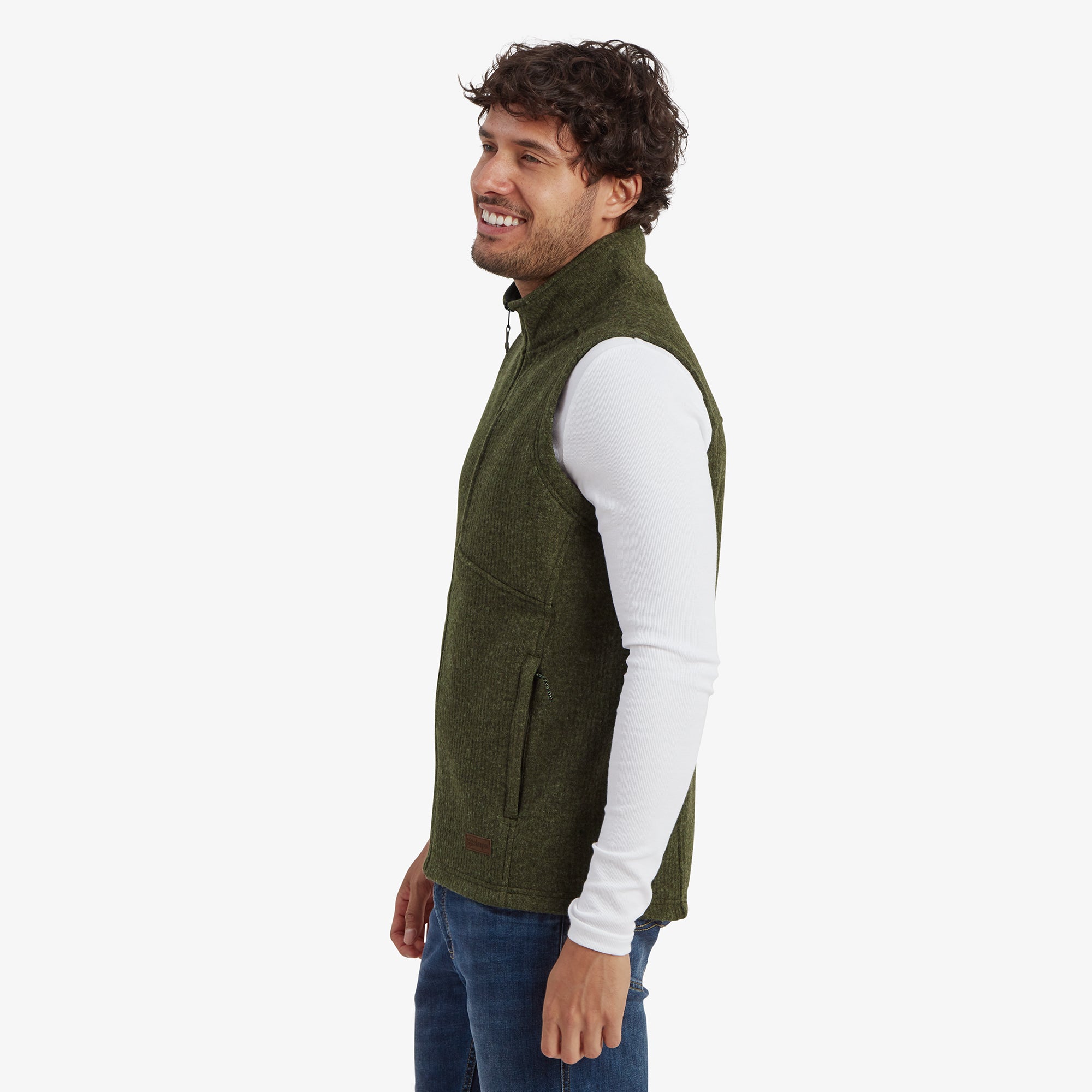 A side view showcasing the Sherpa Adventure Gear Namgyal Vest in Green’s sleek design and fit. The model turns slightly to the side, highlighting the zippered pocket and overall structured cut of the green fabric.