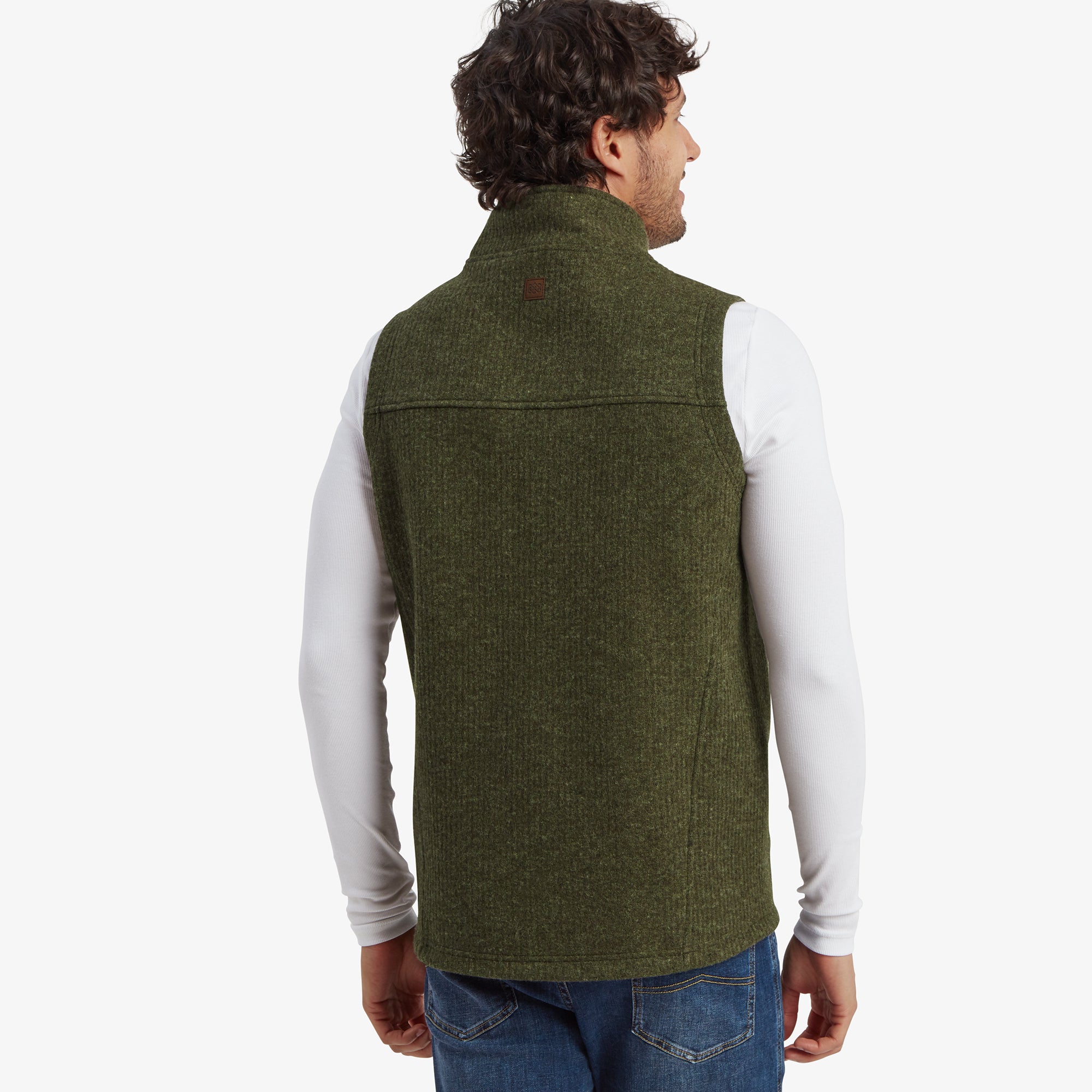 A view of the Sherpa Adventure Gear Namgyal Vest in Green from the back, showing a simple yet classic design with a subtle Sherpa logo near the nape. The green texture is evenly visible, and the outfit is paired with white long sleeves.