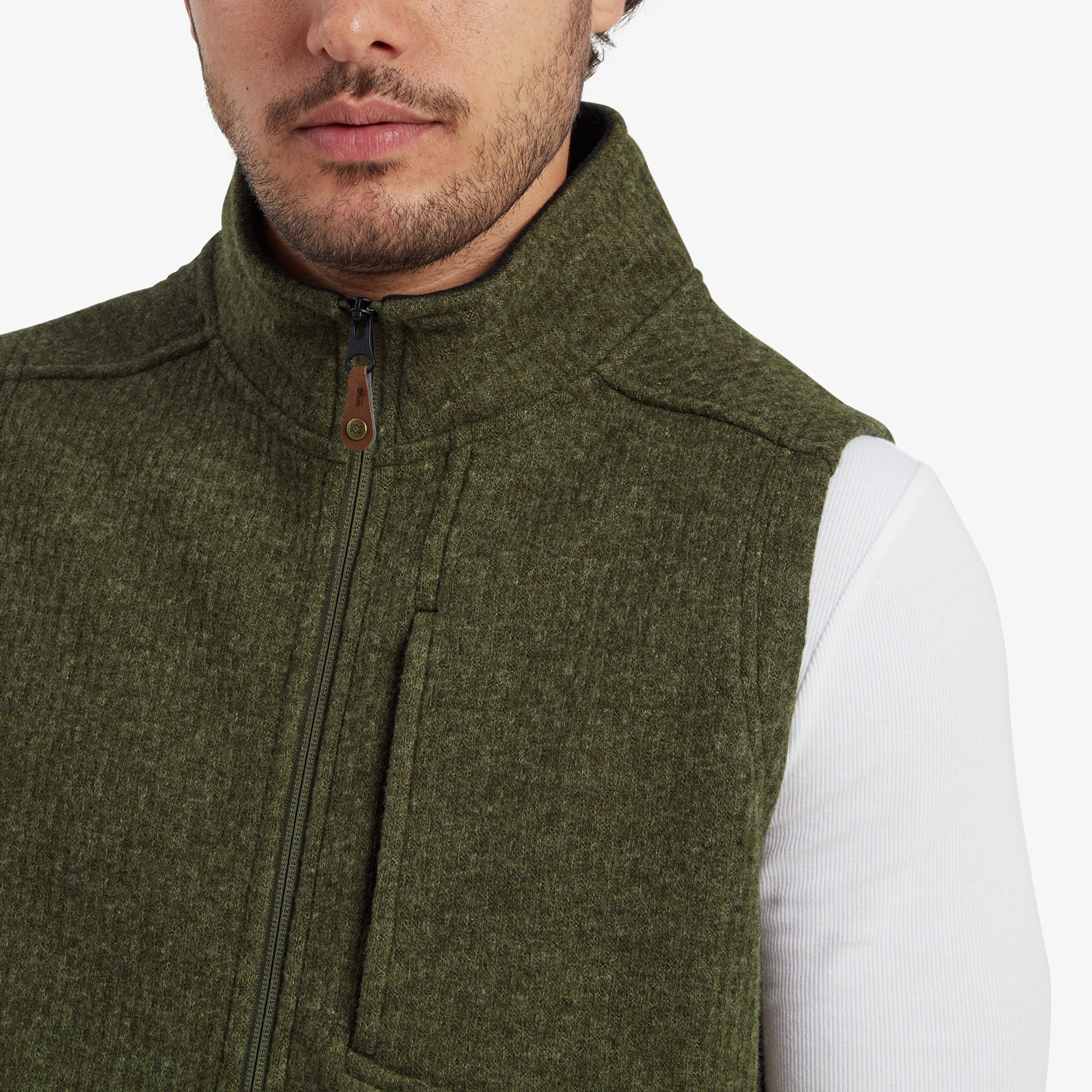 A zoomed-in image of the Sherpa Adventure Gear Namgyal Vest in Green’s zippered chest pocket. The close-up highlights the high-quality green fabric texture, zipper detail, and functional design.