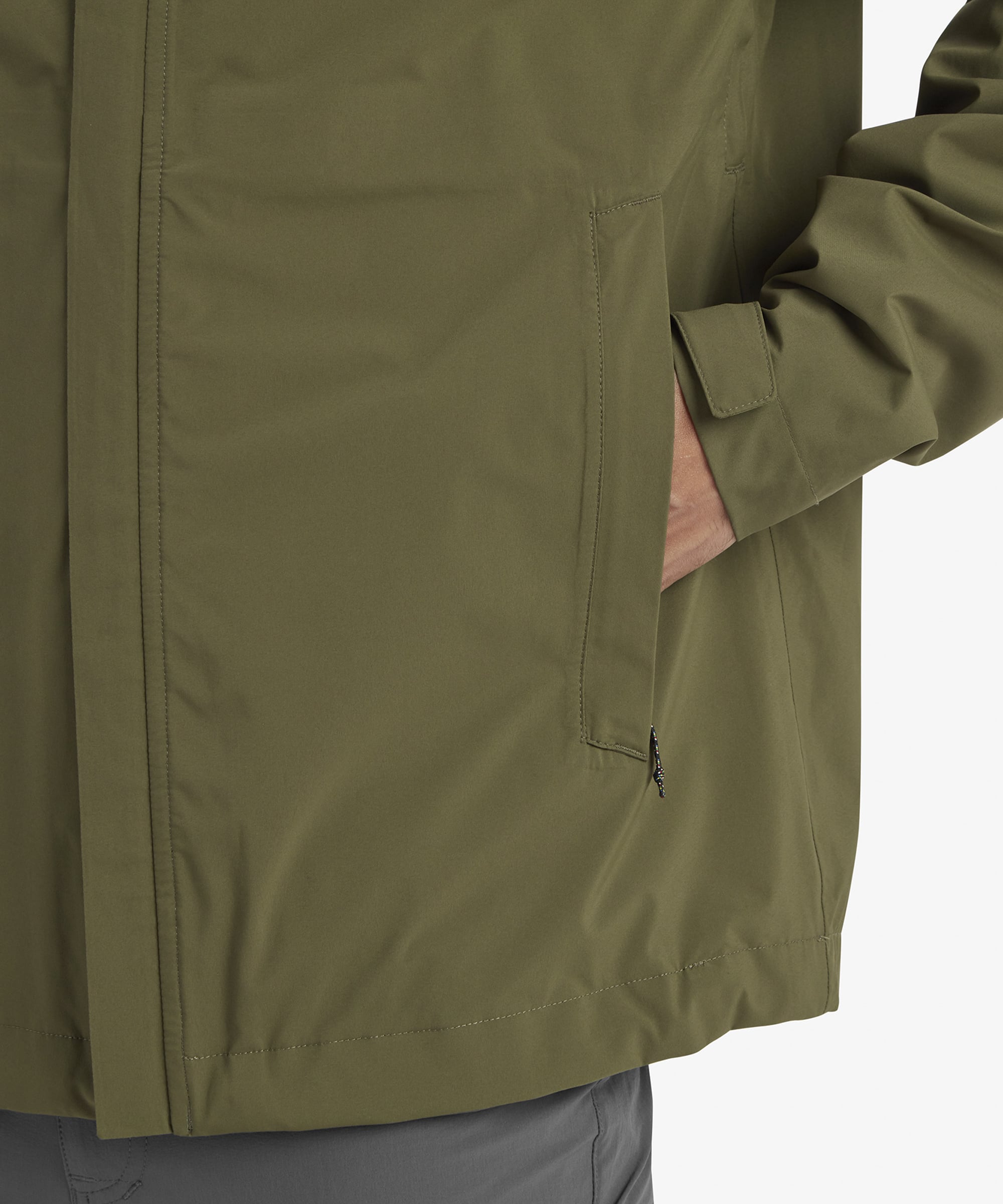 A zoomed-in view of the Sherpa Adventure Gear Nima 2.5-Layer Jacket in Green's chest area, focusing on the Sherpa logo printed in gold on the left side. The image also shows the textured drawstrings of the hood, emphasising the attention to detail.