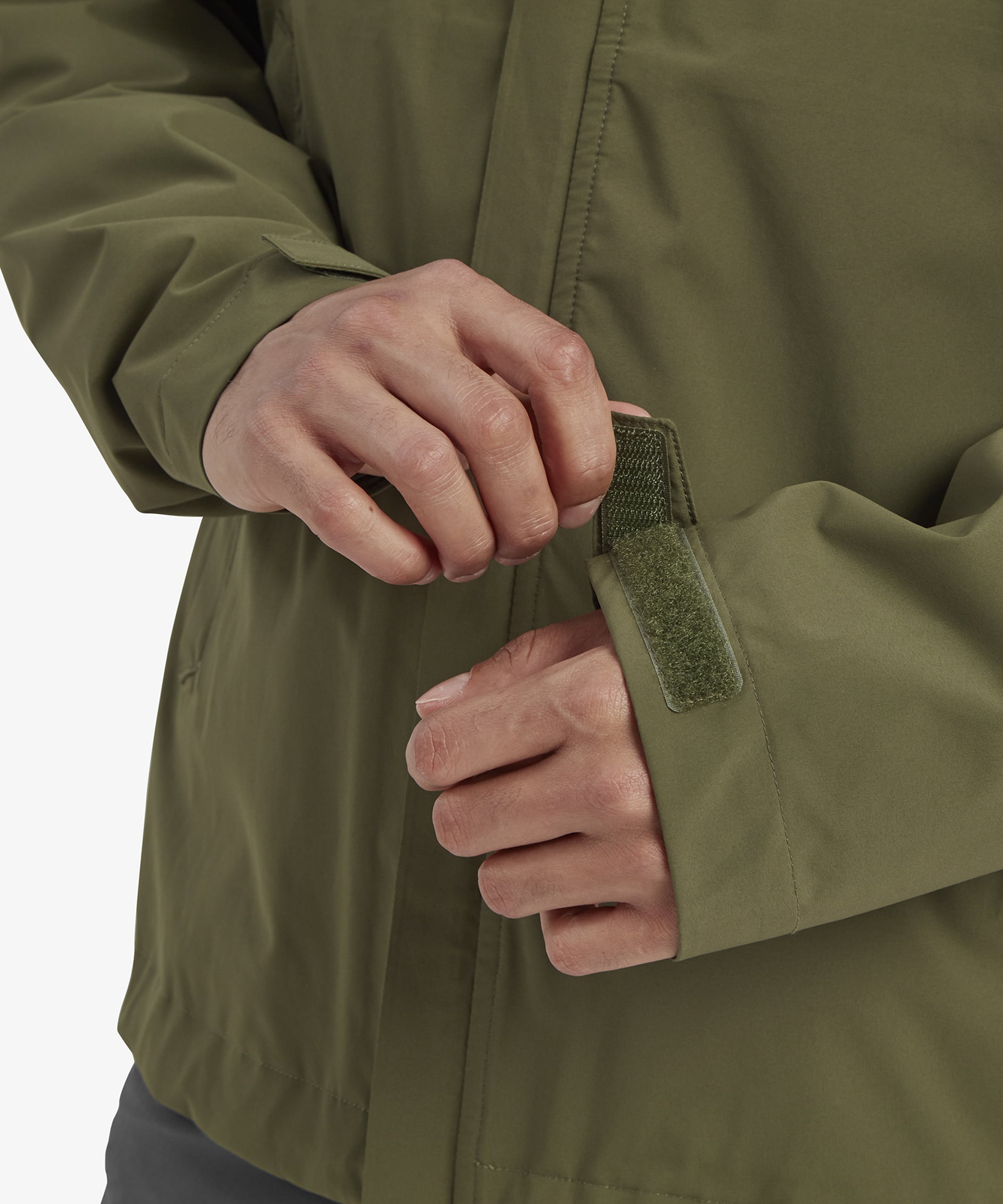 A detailed view of one of the Sherpa Adventure Gear Nima 2.5-Layer Jacket in Green’s front pockets, with a hand partially tucked inside. The pocket’s placement and secure zipper are highlighted, underlining its functional design.