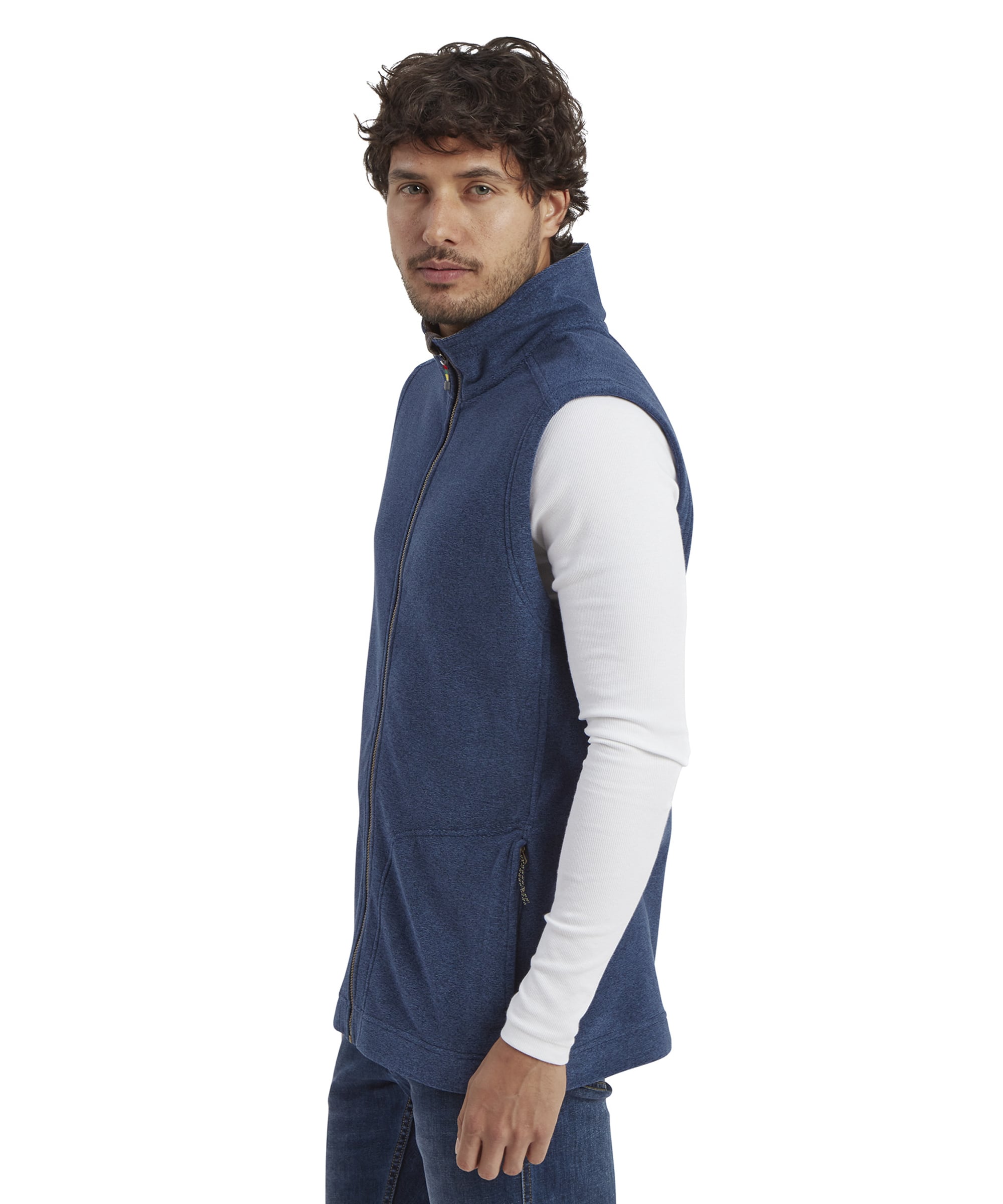 A side profile view of the man wearing the Sherpa Adventure Gear Rolpa Eco Vest in Blue. The vest's clean stitching and tailored fit are visible, along with its soft fleece texture. His posture is relaxed with one arm hanging naturally by his side.