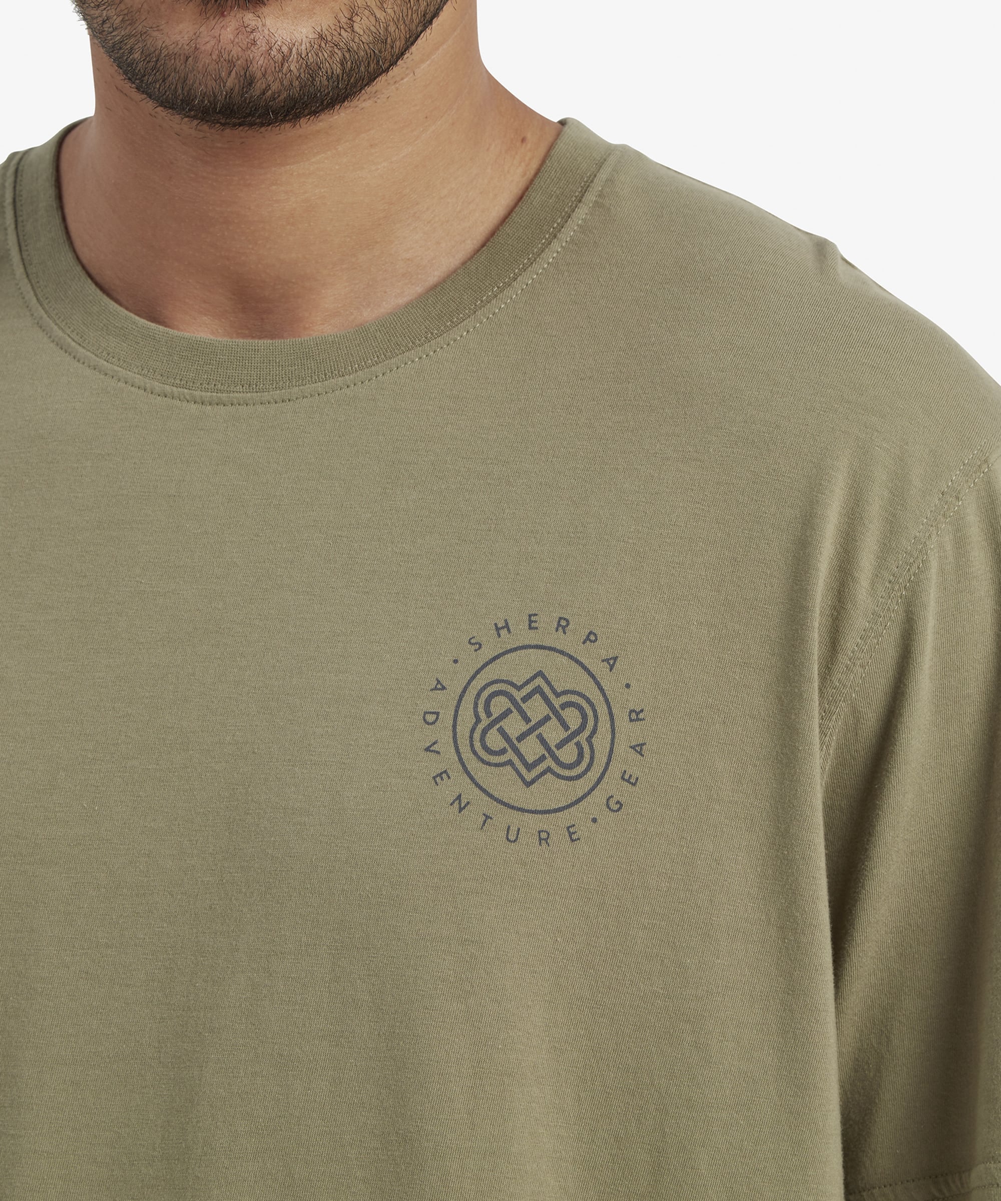 A back view of the same Sherpa Adventure Gear Summit T-Shirt in Green, featuring a bold Sherpa Adventure Gear graphic with a mountain and circular design on the back. The graphic includes shades of blue, gold, and white, emphasising the adventurous theme of the brand.