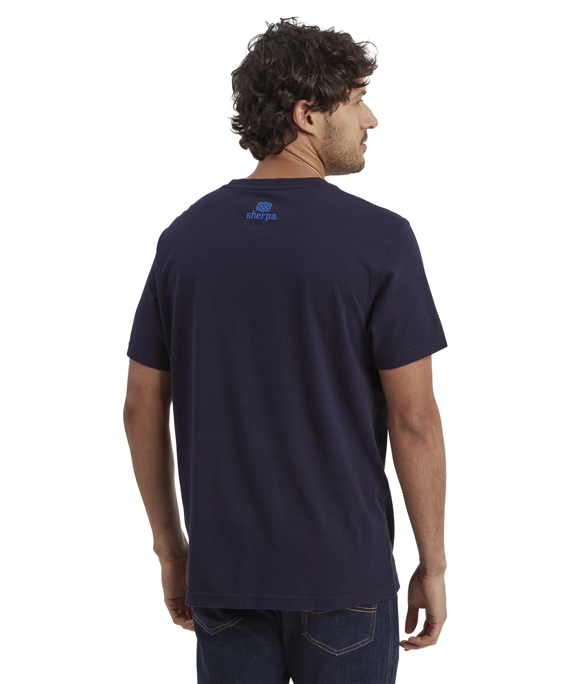 The back of the Sherpa Adventure Gear Tarcho T-Shirt in Blue features a small Sherpa Adventure Gear logo in blue near the neckline. The model's back posture highlights the t-shirt's seamless design and comfortable fit.