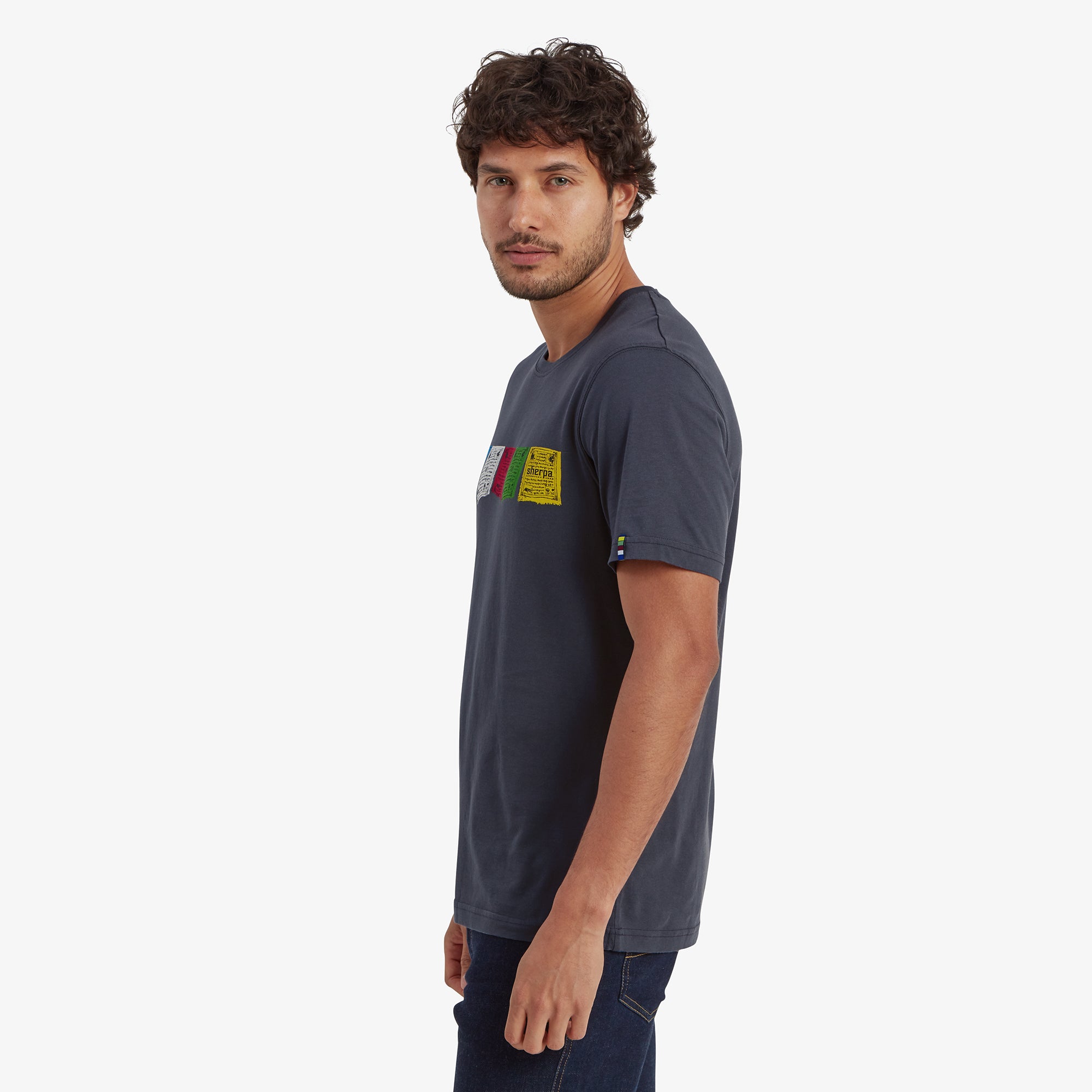 A profile of the male model turned slightly to the side, highlighting the slim fit of the Sherpa Adventure Gear Tarcho T-Shirt in Grey and how it drapes naturally over his shoulders and arms.