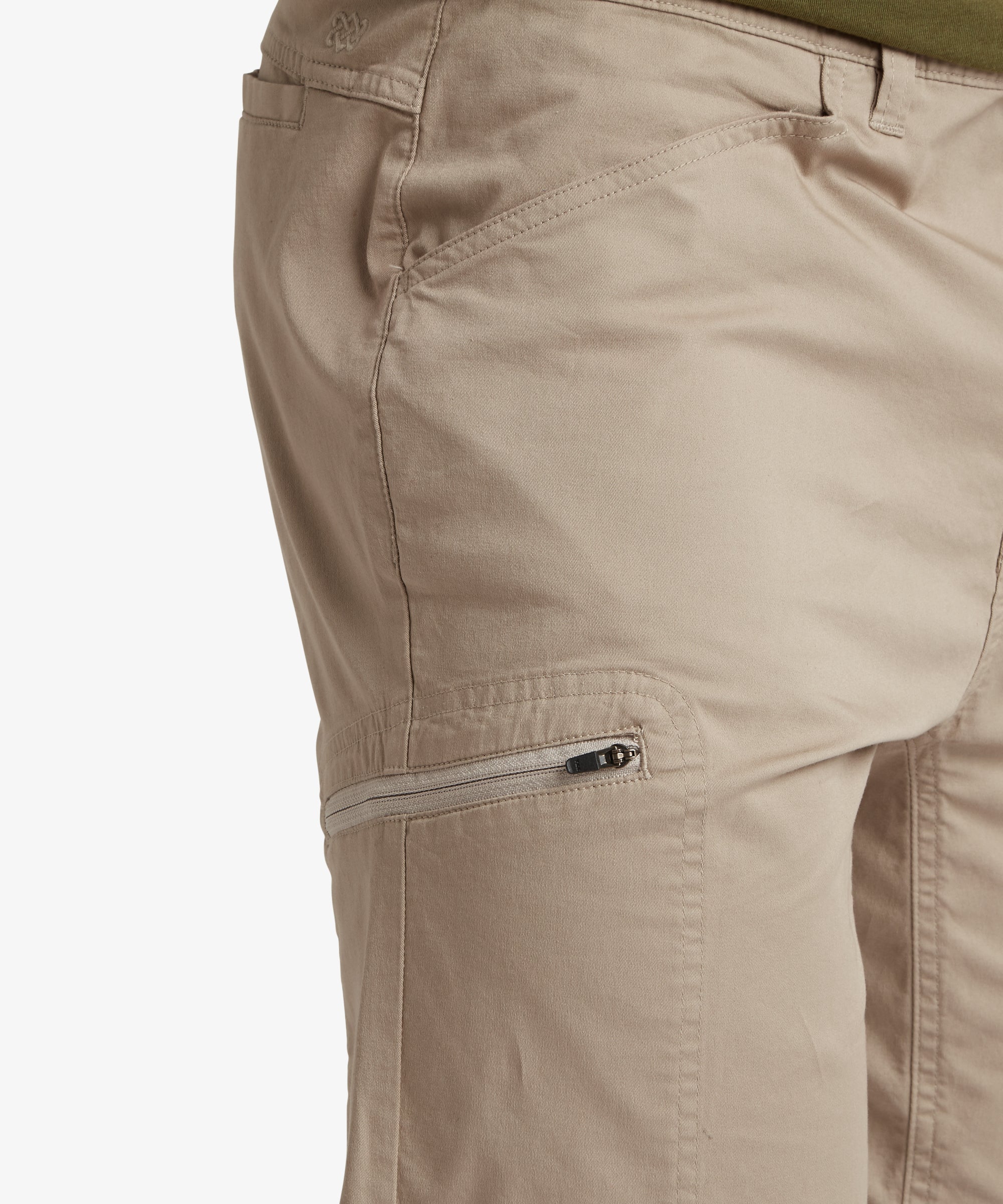 A slightly angled back view of the Sherpa Adventure Gear Tenjing Shorts in Beige, focusing on the fit around the waist and thighs. The flip-flops and the model’s relaxed pose contribute to the laid-back style of the outfit. The clean stitching details and subtle branding are visible.