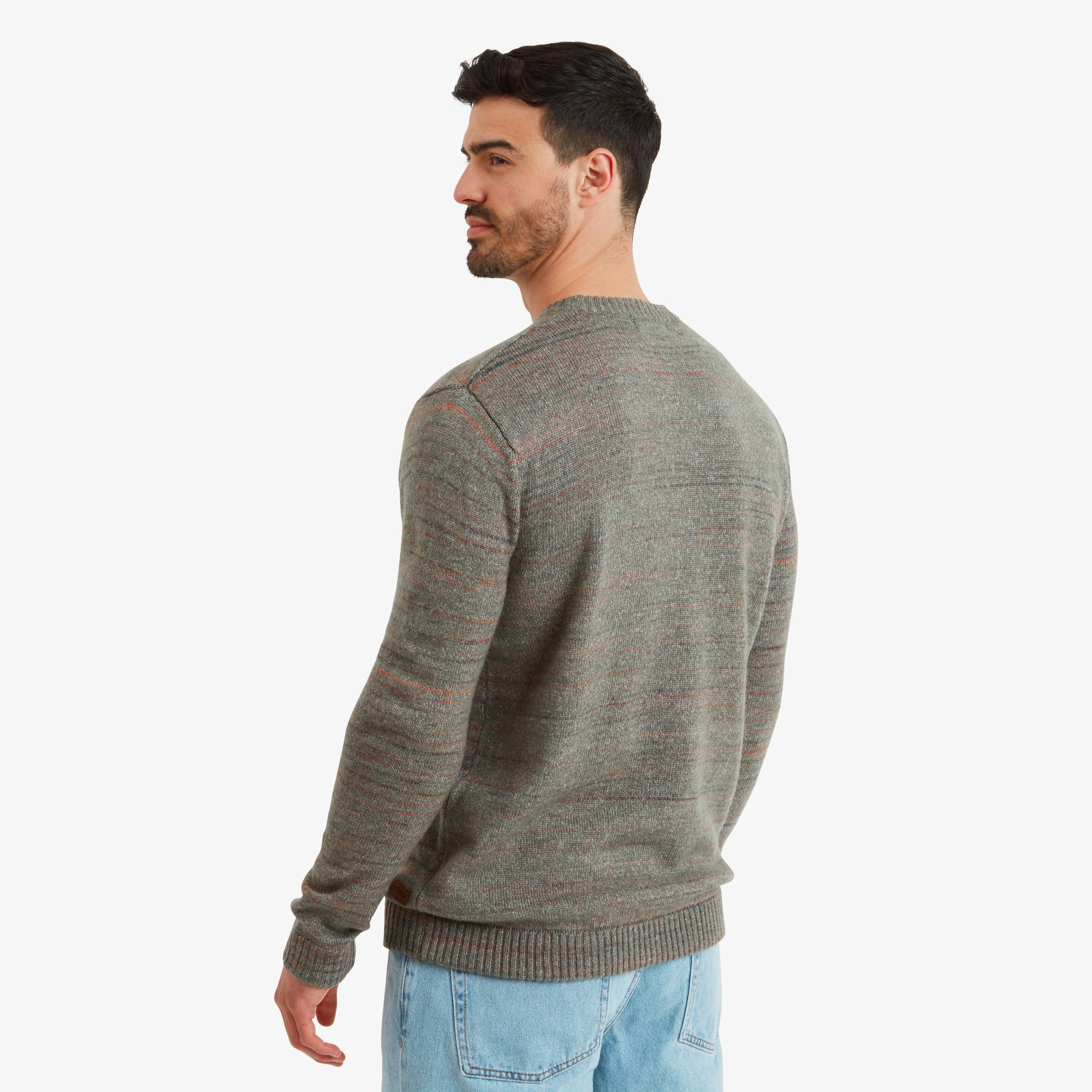 A rear view of the Sherpa Adventure Gear Vidvan Crew in Grey, emphasising its neat construction and ribbed hemline. The light gray knit texture and faint orange accents add to the garment's understated style. The man stands casually with hands relaxed at his sides.