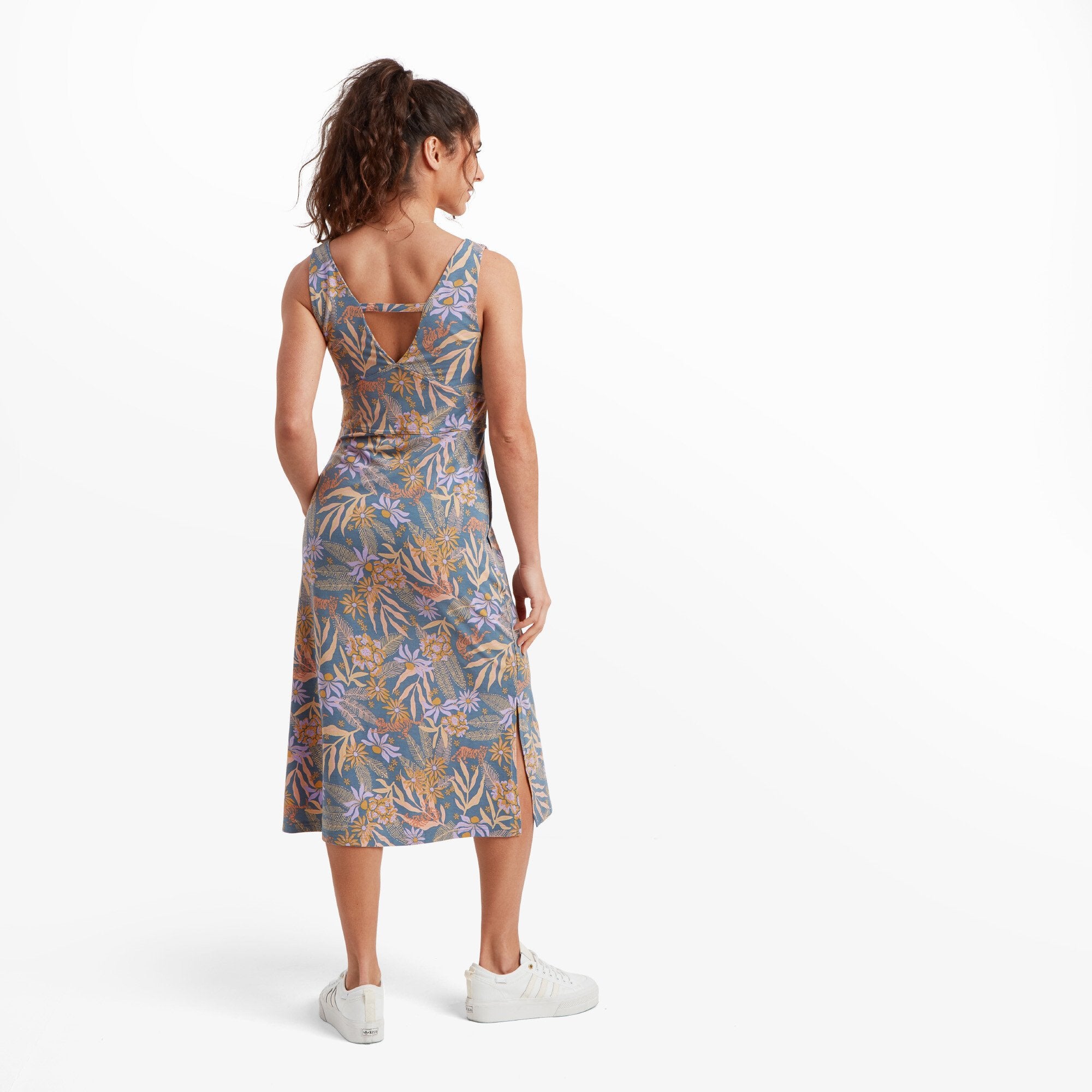 The back of the Sherpa Adventure Gear Neha Midi Dress in Blue features a V-shaped cutout with a delicate horizontal strap for detail. The pattern continues seamlessly, highlighting the design's vibrant yet balanced nature. The hem reaches mid-calf, emphasising its midi length.