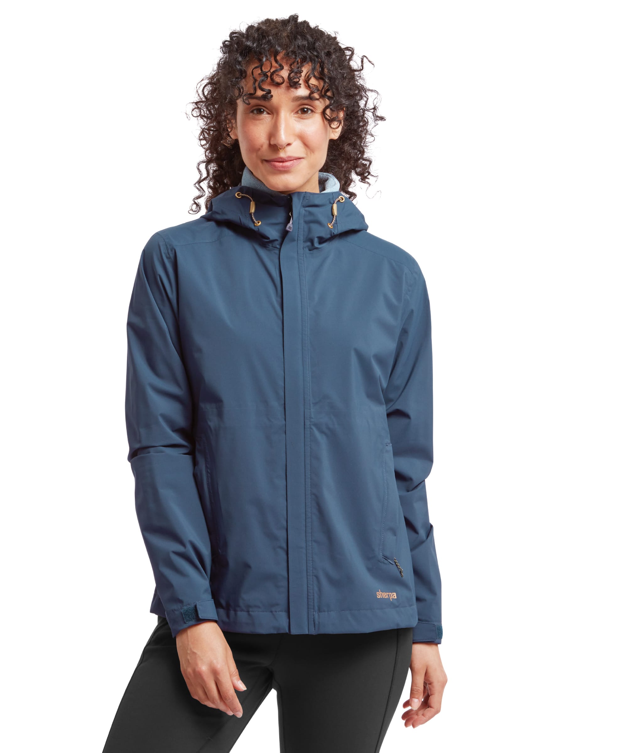 The model is wearing the Sherpa Adventure Gear Nima 2.5-Layer Jacket in Blue, zipped up completely. The hood is up, with drawstrings visible. The overall fit and structure of the jacket are clearly displayed.