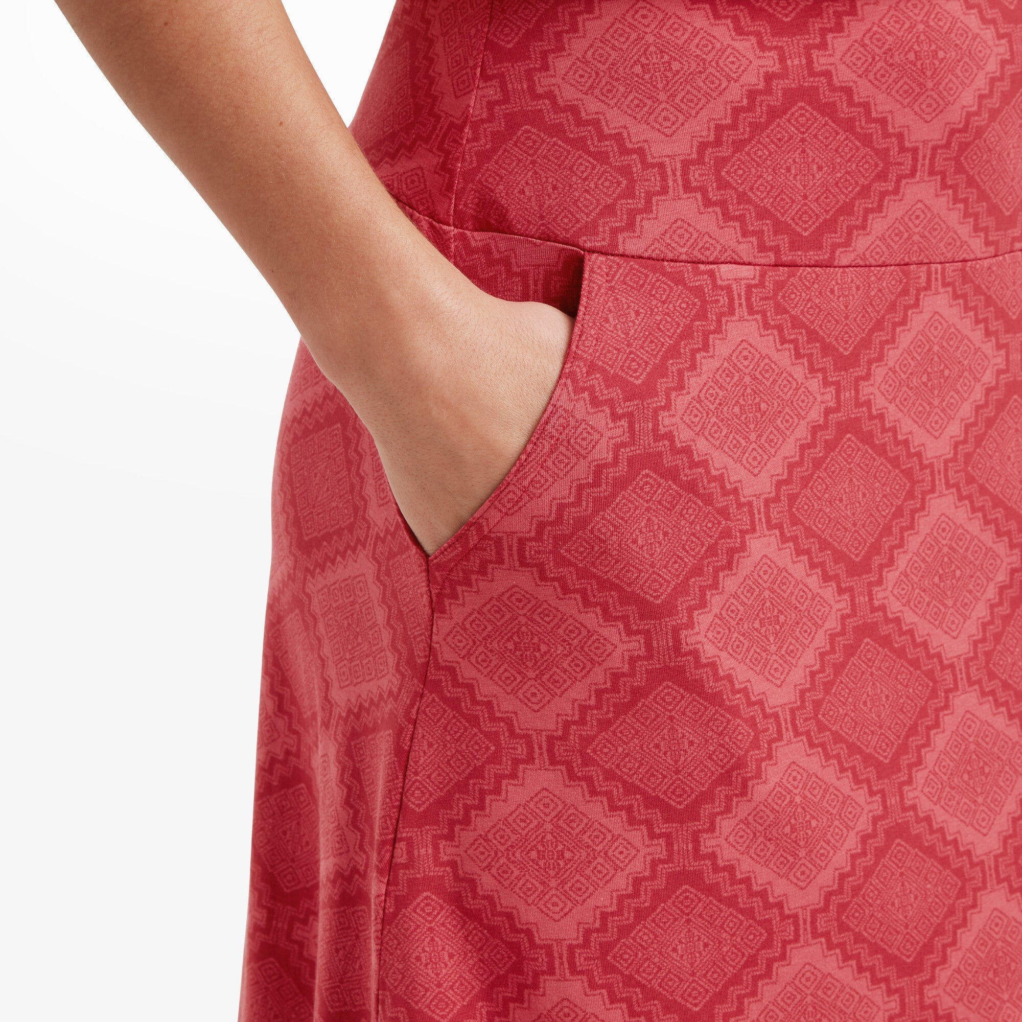 A detailed shot of a woman's hand tucked into the side pocket of the Sherpa Adventure Gear Padma Pull On Skirt in Red. The intricate pattern is clearly visible, and the pocket blends seamlessly into the design. The texture of the fabric is highlighted, showing its quality and craftsmanship.