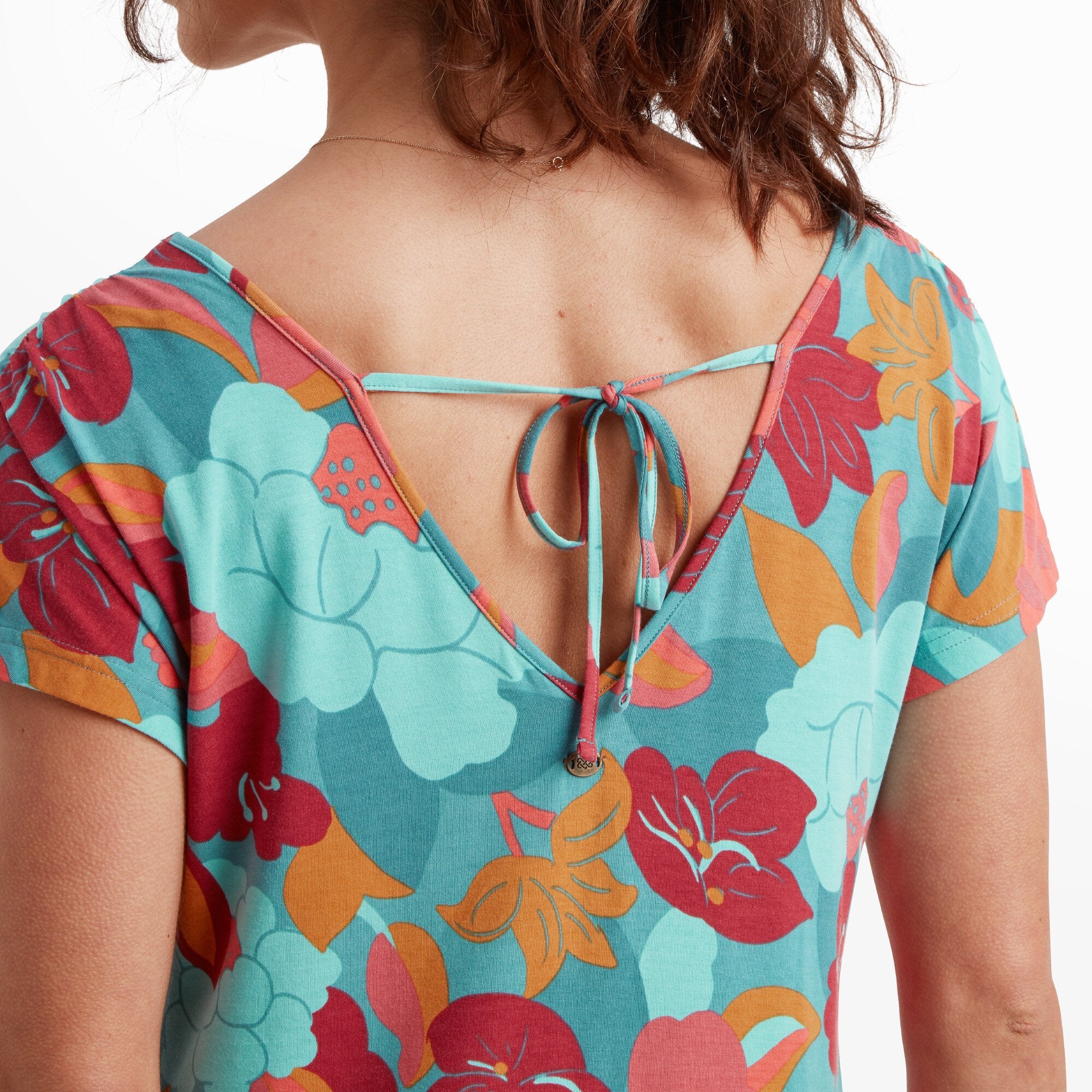 A close-up view of the tie-back detail on the Sherpa Adventure Gear Padma Tie Back Dress in Blue. The tie is neatly secured, and the V-shaped back accentuates the colorful floral print. The fabric's soft texture and vivid colors are prominent in this image.