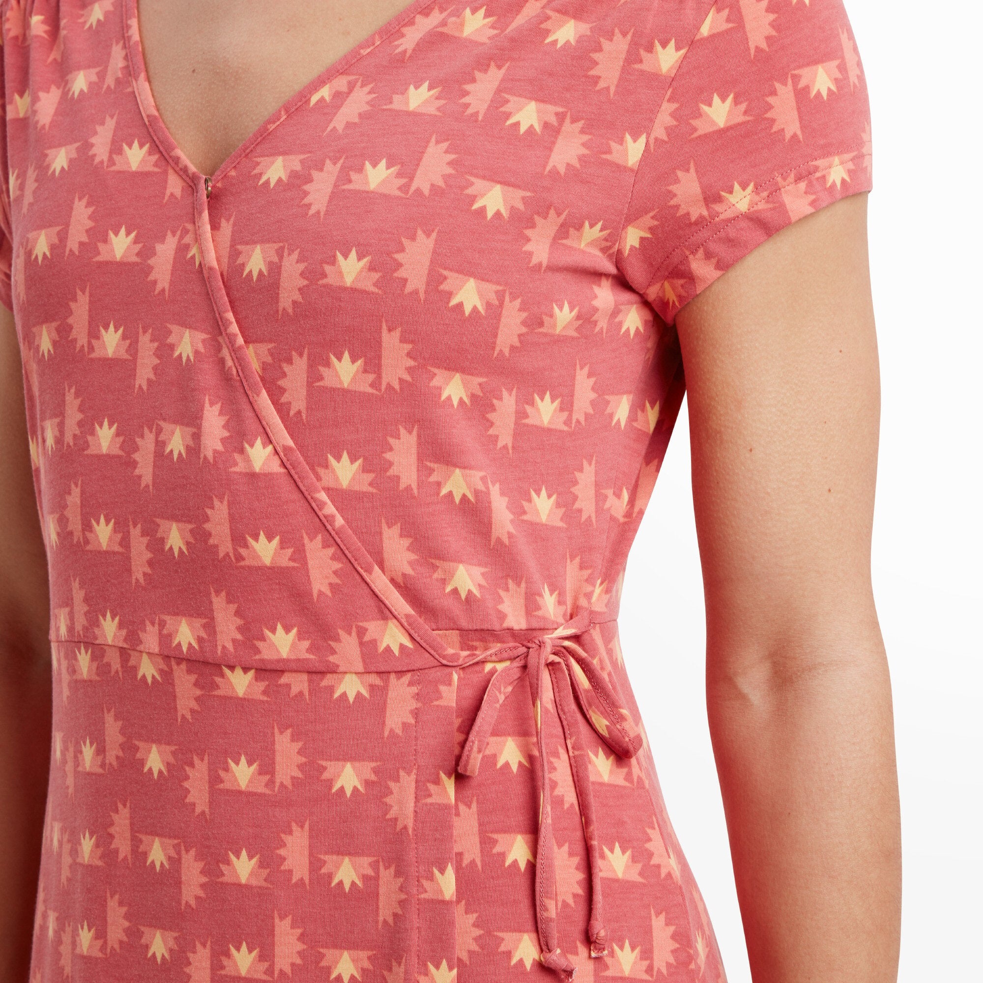 A close-up of the wrap detail on the Sherpa Adventure Gear Padma Wrap Dress in Red. The tied waist is visible, emphasising the fitted style at the waist. The geometric print and clean seams add a polished touch.