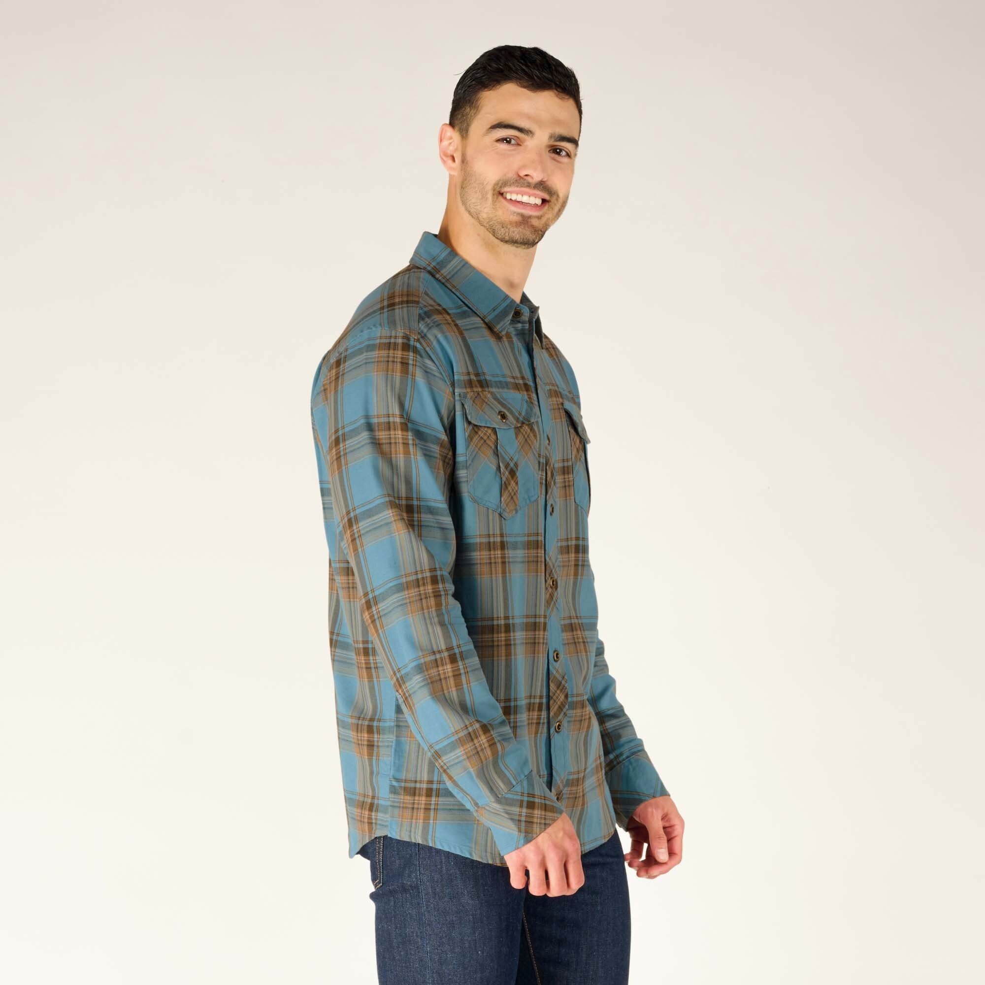 A side-angle view of the male model in the same Sherpa Adventure Gear Ramoche Shirt in Grey, highlighting the fit of the shirt on the shoulders and chest. The long sleeves are fully buttoned, and the model smiles slightly.