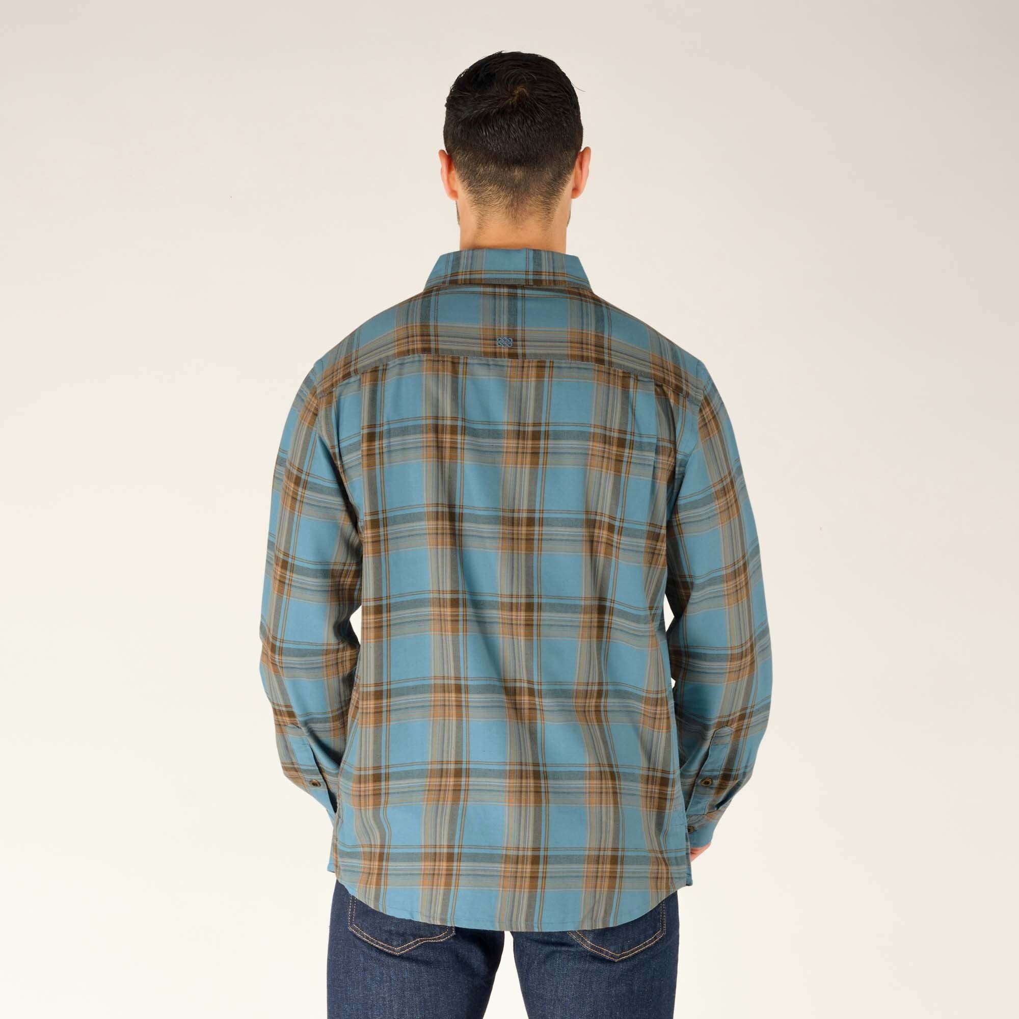 The back of the Sherpa Adventure Gear Ramoche Shirt in Grey is showcased, displaying the plaid pattern continuity and the straight hem. The model's arms are relaxed, and the shirt falls naturally over the dark jeans.