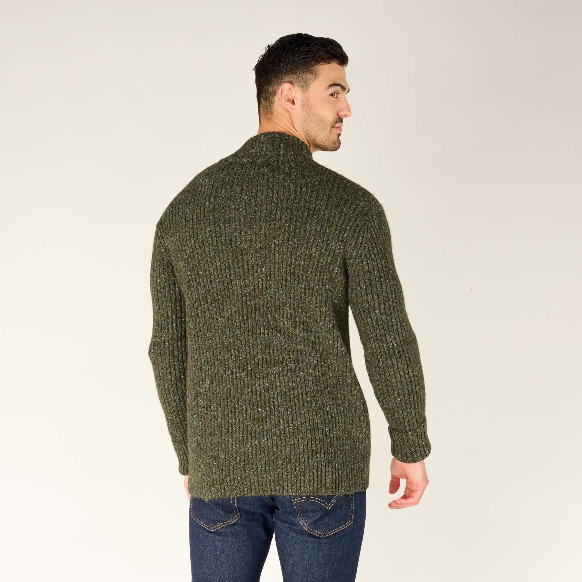 A rear view of the man in the same Sherpa Adventure Gear Ranga Button Mock Neck in Green, showing the ribbed knit texture continuing seamlessly across the back. The fit is snug but comfortable, paired with dark jeans for a casual look.